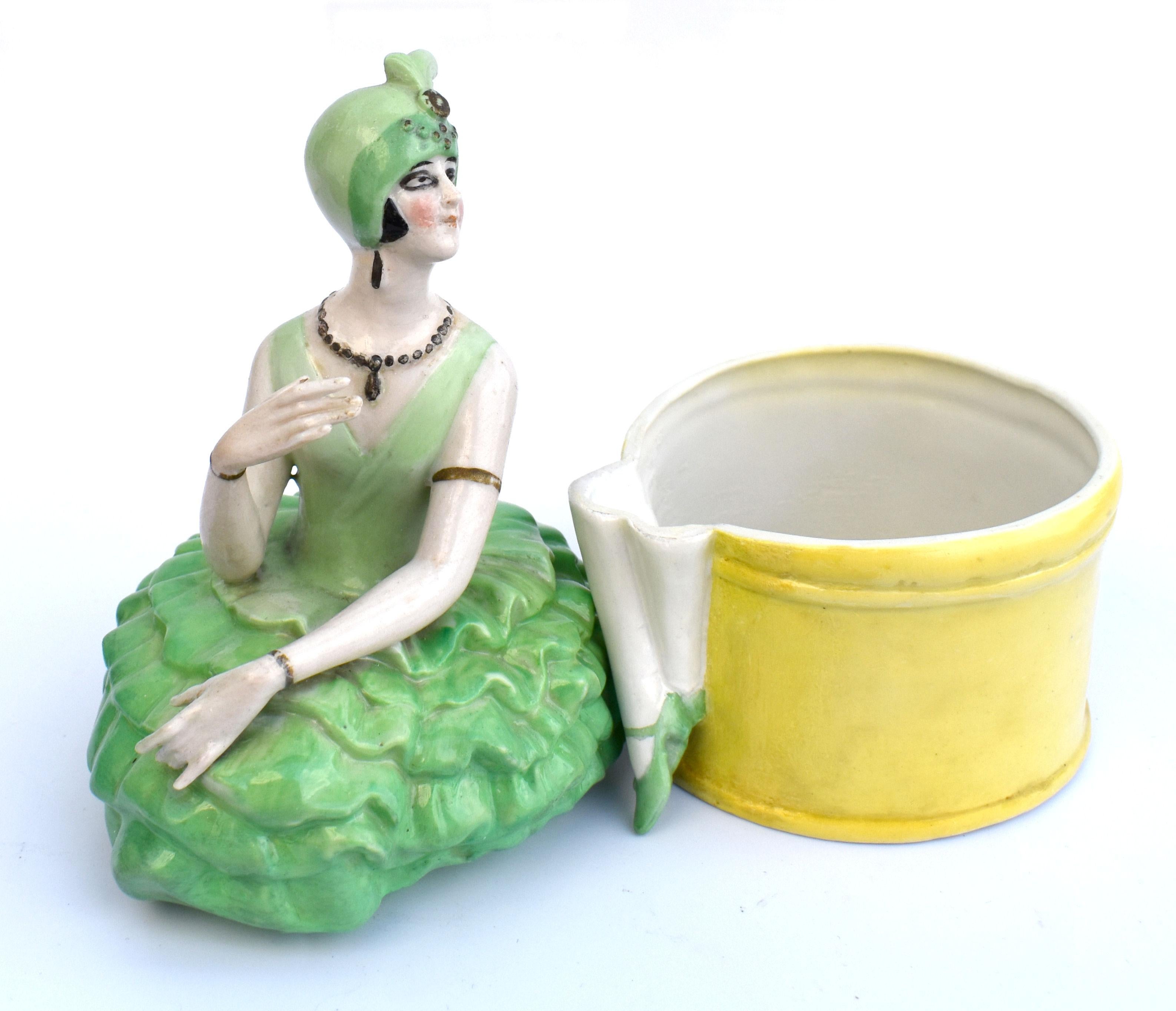 Striking and quite rare is this 1930s Art Deco ceramic powder box which depicts a stylized female dancer sat on hat box. We think she's German in origin and although not marked, only impressed factory numbers we think she's likely from FASOLD &