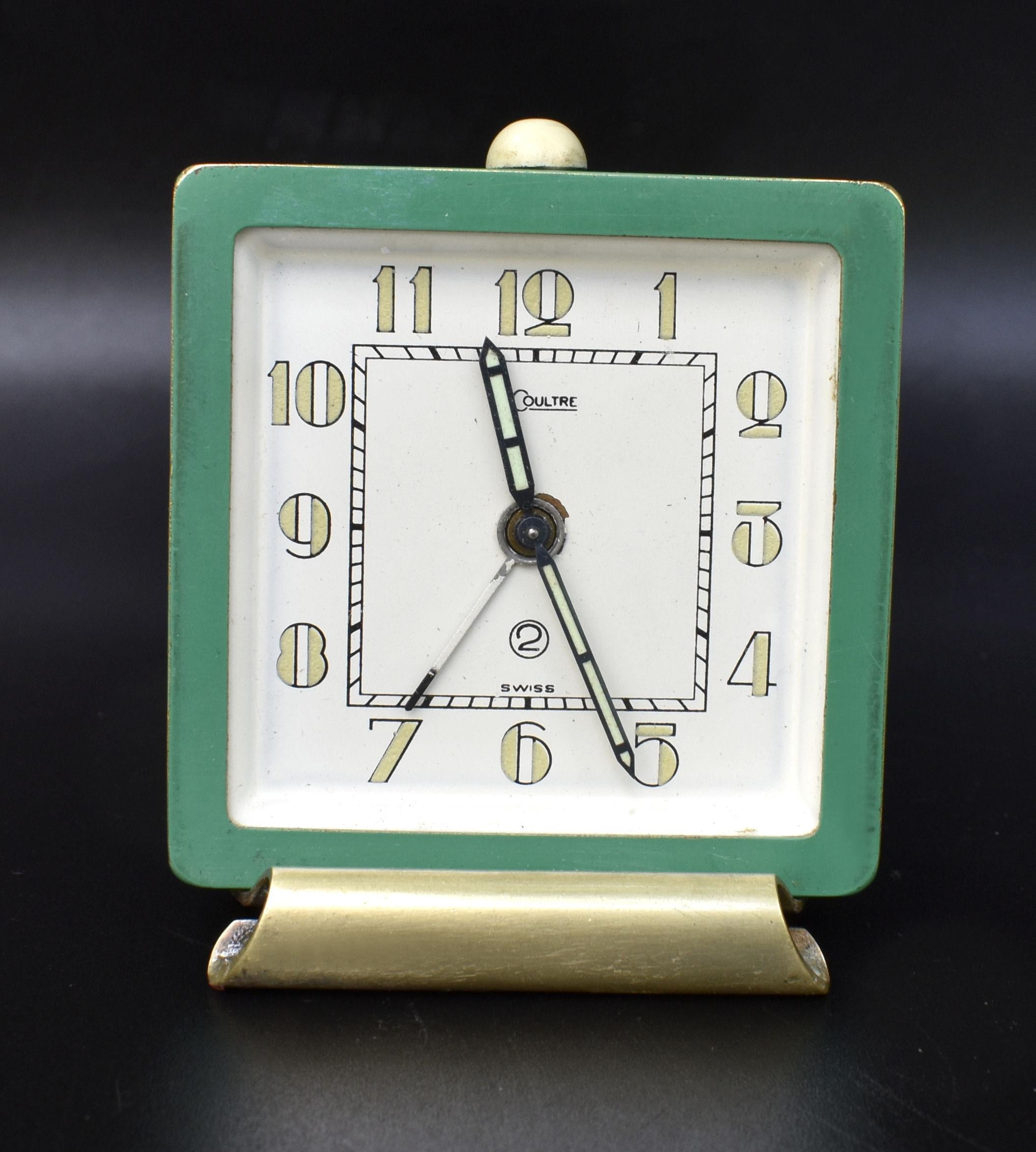 This is for a beautiful original and extremely stylish art deco desktop alarm clock made by Jaeger LeCoultre. It dates to the 30s, it has a 2 day movement and it has a green enamel body with a gilded stand and stylised art deco numerals. The face is