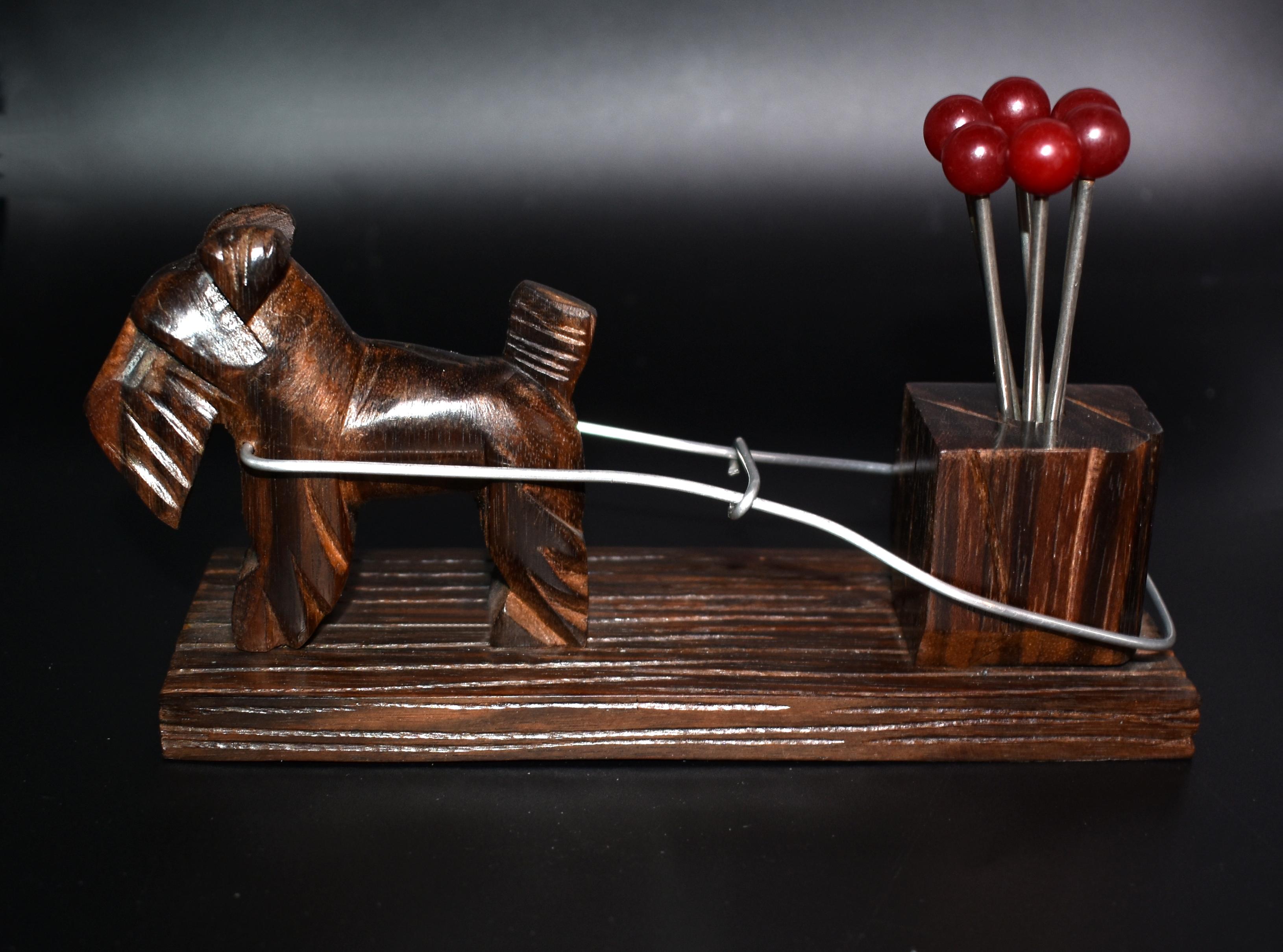 A rare novelty 1930s cocktail stick set originating from France. Features a harnessed Scottie dog 'west highland terrier ' pulling along a trunk of wood which is carrying a group of cherry red colored Bakelite cocktail sticks with chromed metal