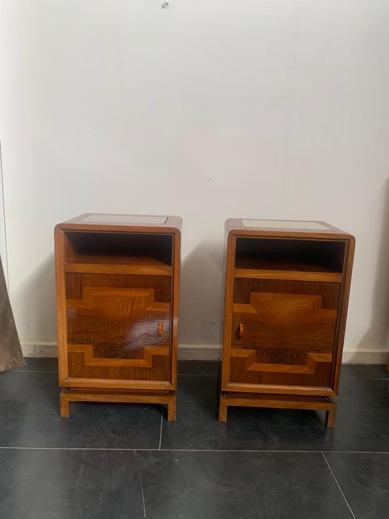 Pair of rationalist bedside tables in walnut, walnut burl and maple. Splendid rationalist handles in chrome metal and pastel orange bakelite. On the top there is a compartment for fabric storage (to be replaced) with glass above. The lines echo the