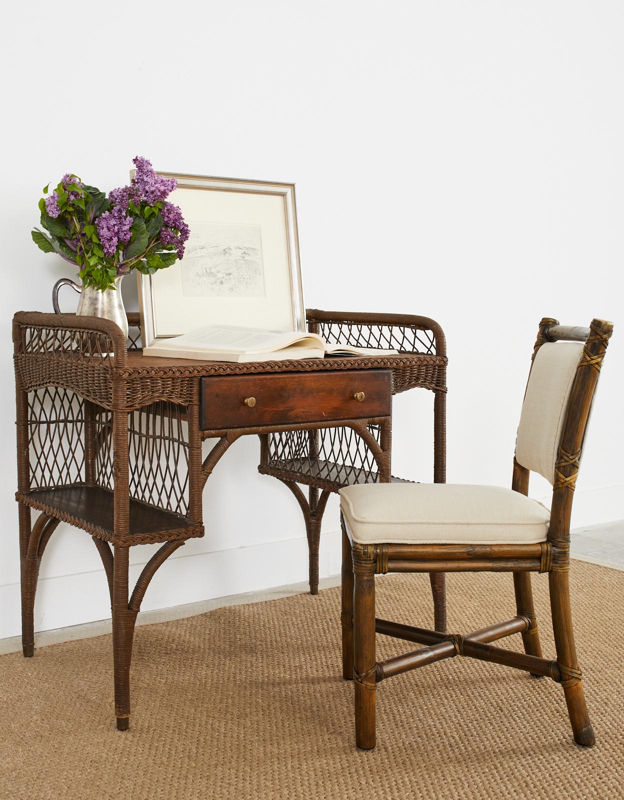 Sculptural art deco writing table or desk attributed to Heywood Wakefield. The desk features gracefully curved rattan arches and features a small bookshelf on each side. The maple top has a galleried edge crafted from rattan wrapped with wicker