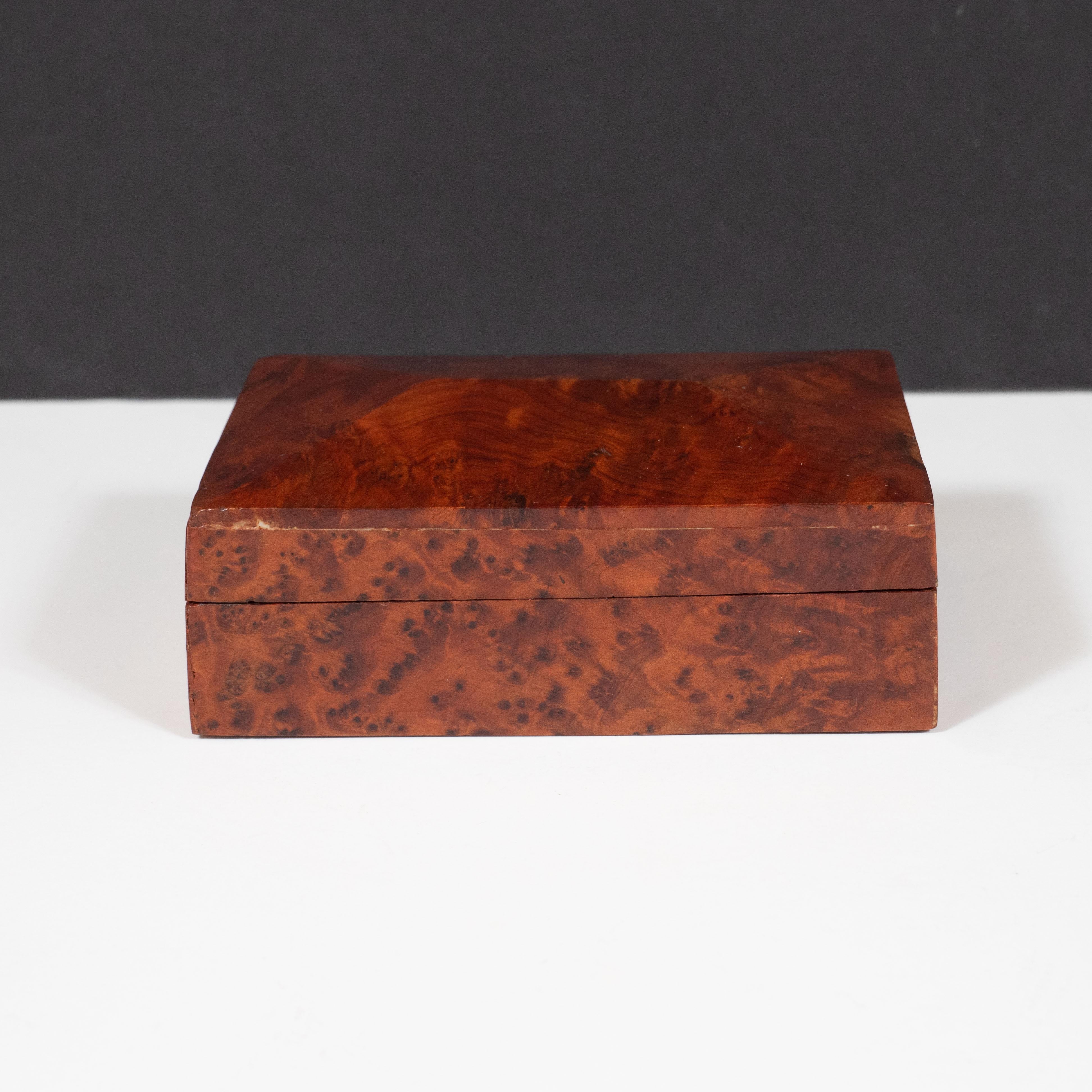 This elegant Art Deco box was realized in the United States circa 1960. It features a rectangular form in beautiful burled carpathian elm that showcases the naturally exquisite grain of the wood, as well as a peaked and faceted top. Organic, refined