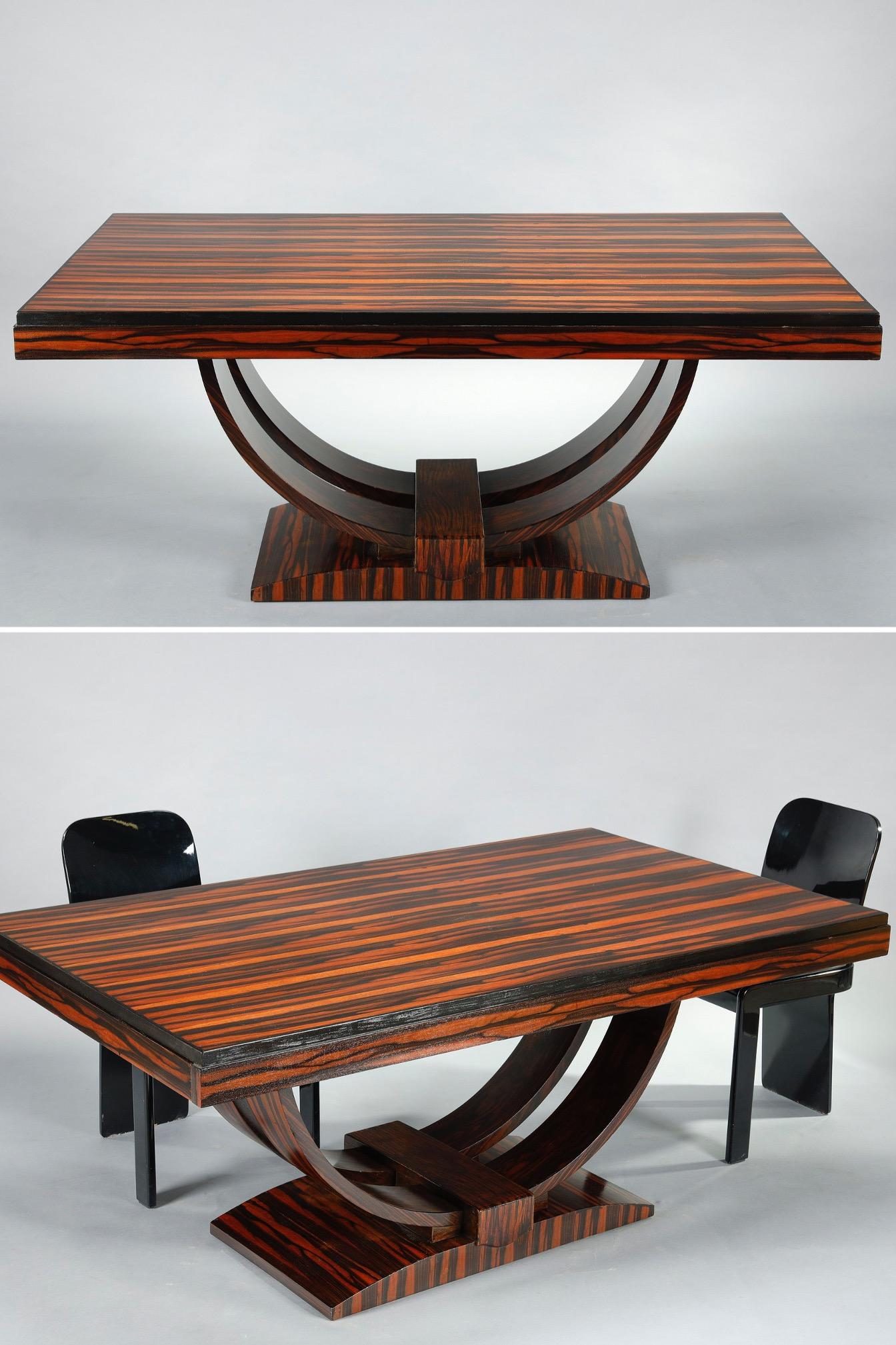 Rectangular Art Deco dining table in Macassar ebony veneer, resting on a double curved pedestal and opening to two side drawers. The elegance, sobriety and nobility of materials are typical of the period.