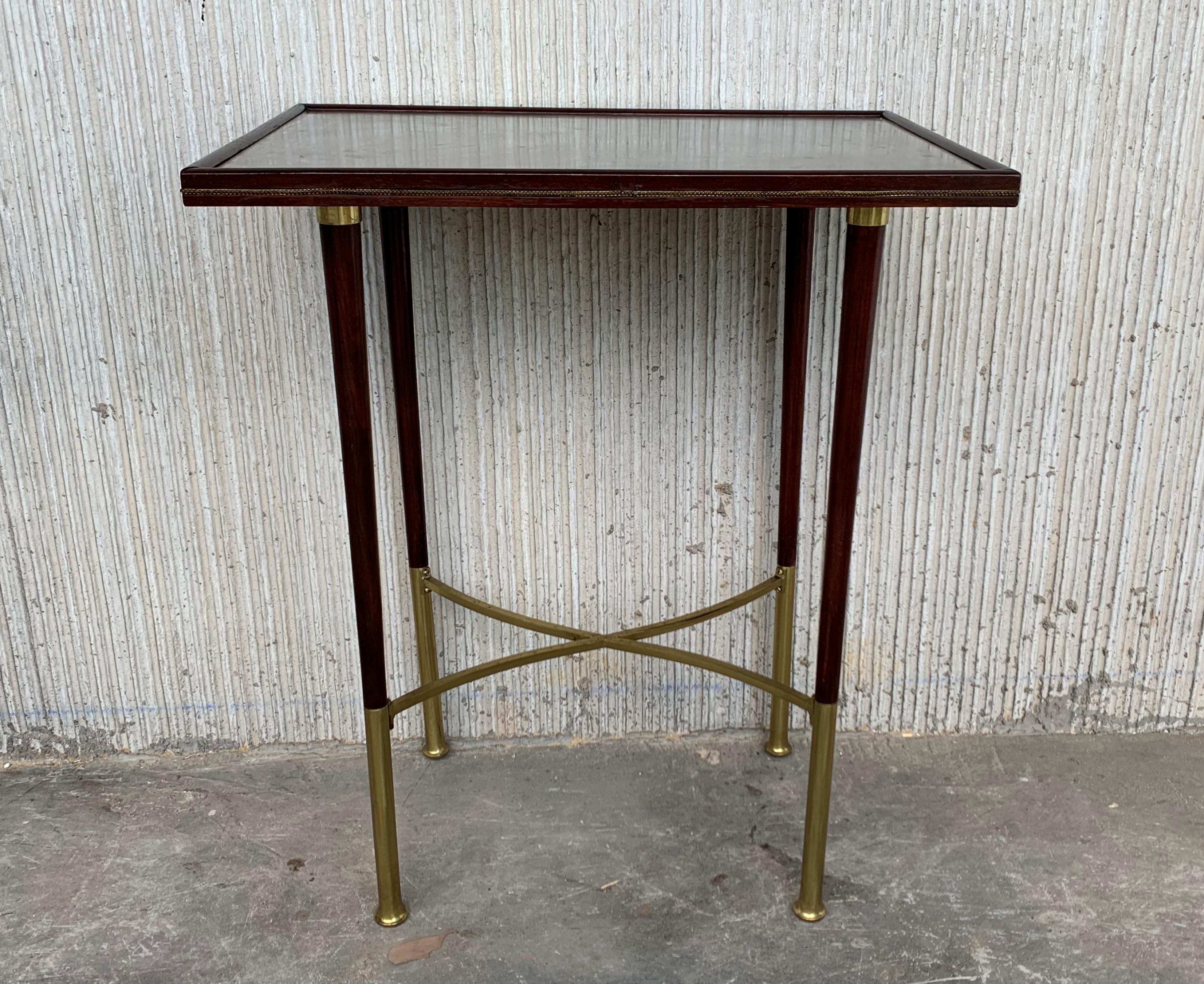Art Deco top side table with mahogany top covered with a glass and tapered legs with brass feet joined with a cross piece.