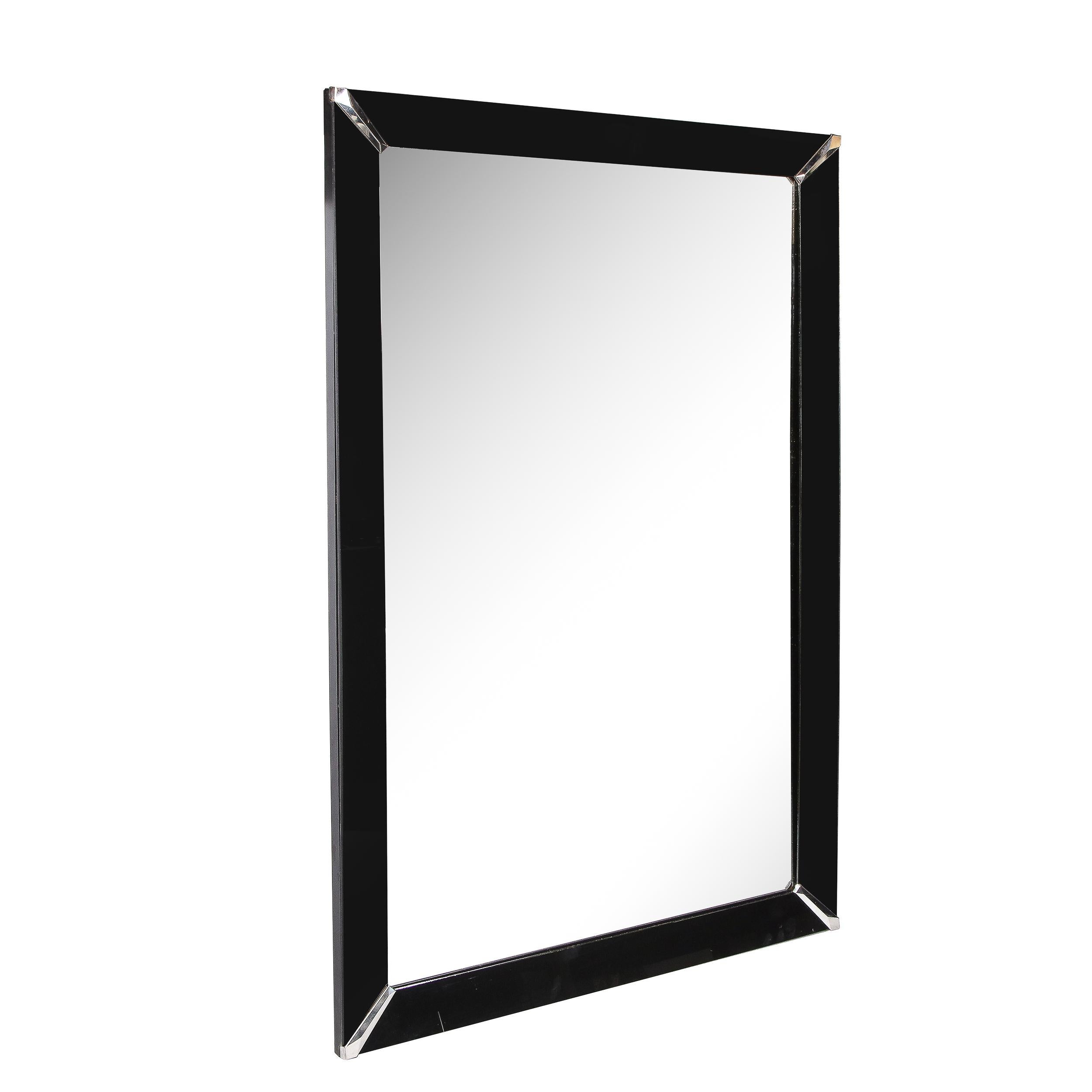This elegant and understated Art Deco mirror was realized in the United States circa 1930. It offers a rectangular form composed of four segments of black vitrolite adjoined in each corner by darted pentagonal polished chrome embellishments- that