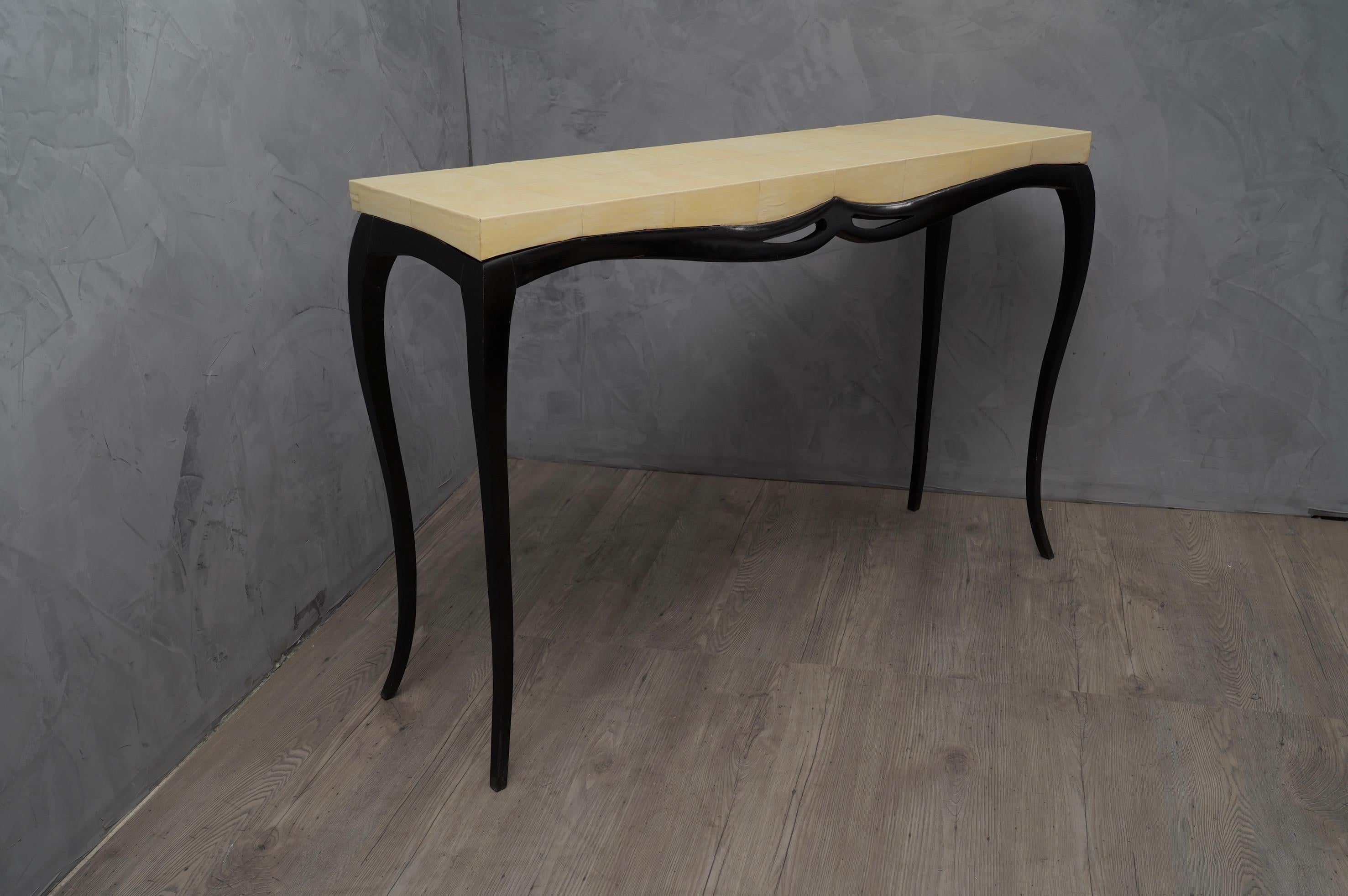 Very rich in movements, this console is unique in its kind also for the precious material with which it is coated.

The console is made up of a wooden top covered in goatskin, where the leather also covers the part of the side edge; The top rests
