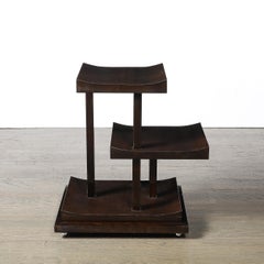 Mesita auxiliar art déco de tres niveles, de líneas rectas y curvas, de madera de nogal, con base en forma de zócalo
