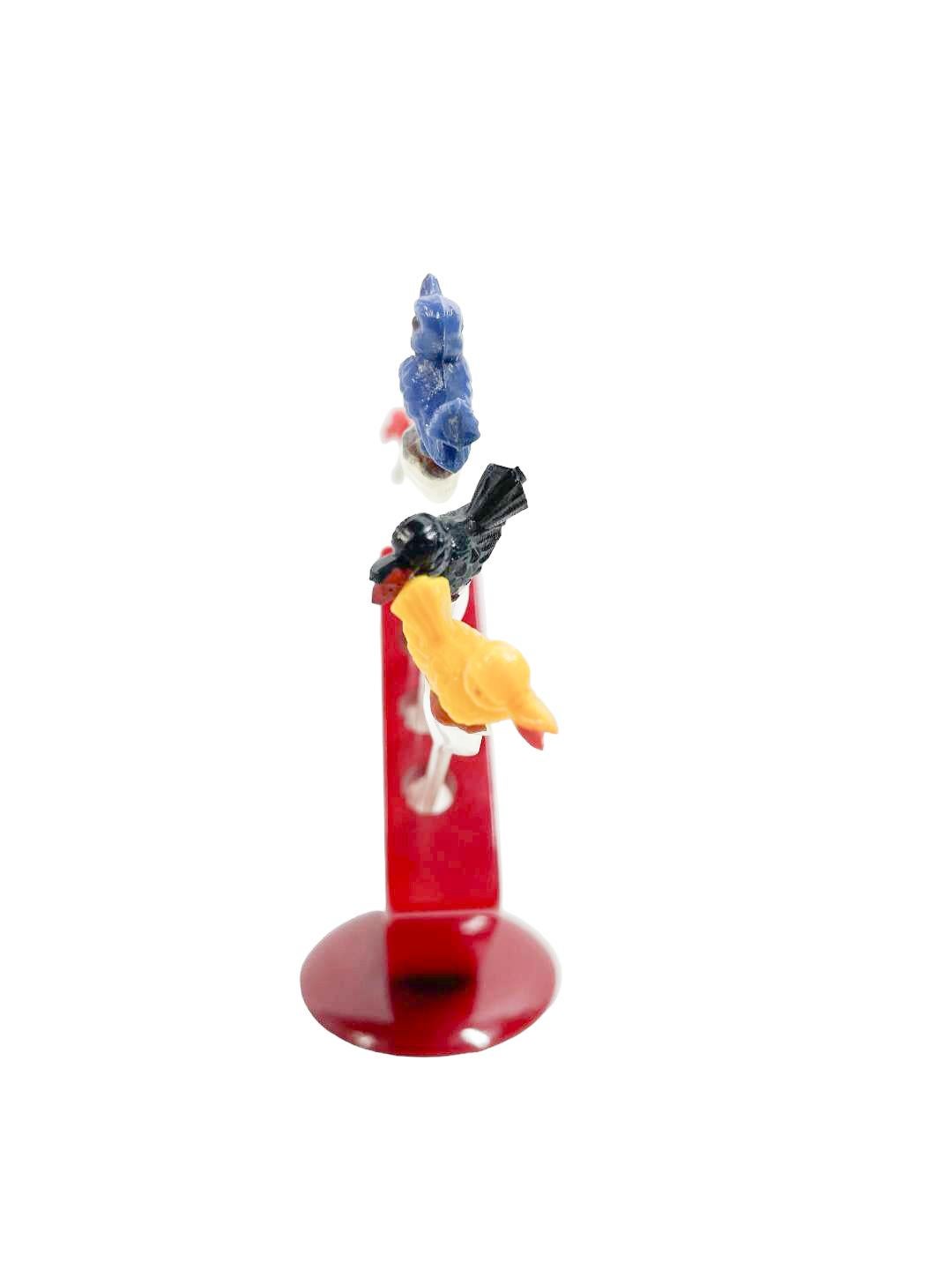 Lot de 6 piques à cocktail en plastique transparent avec des têtes d'oiseaux colorées dans un support géométrique en bakélite rouge.