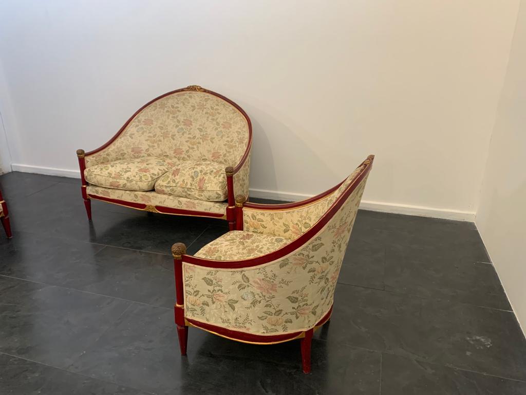 Prestigious and unique sofa with matching pair of Art Deco armchairs. Lacquered cardinal red with finely carved knobs and gold leaf appliqués. Upholstery in generously thick jacquard fabric, this is a floral lampas with gold filaments depicting