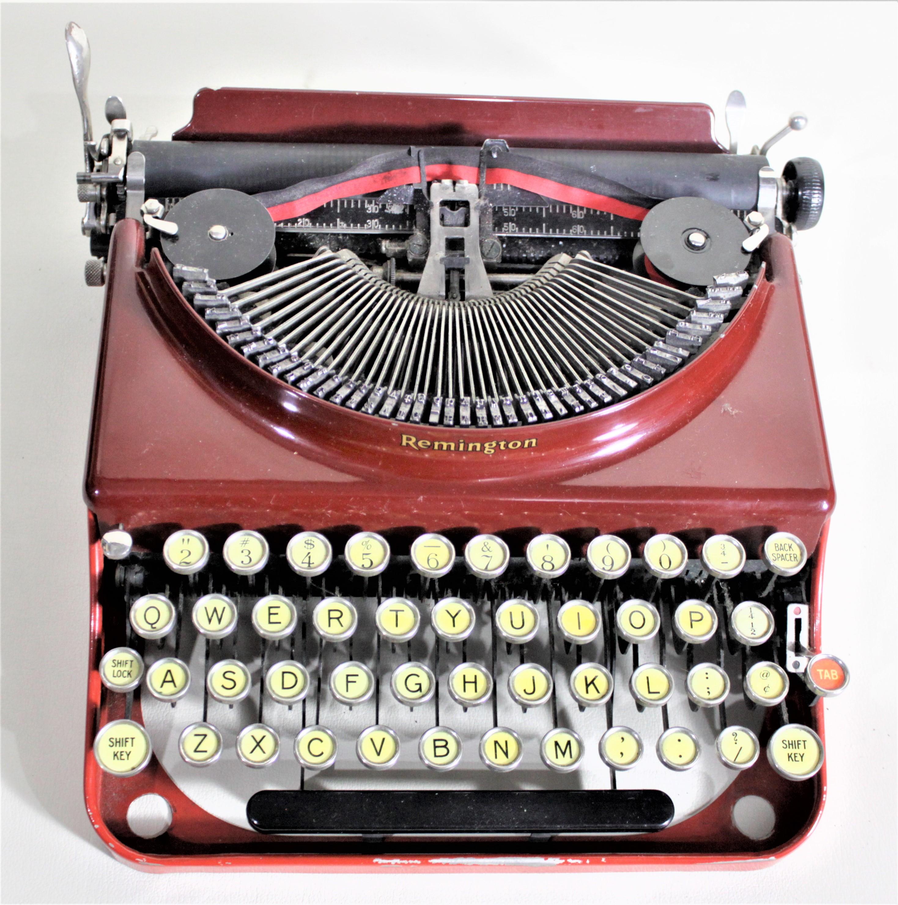 This red Art Deco streamlined portable typewriter was made by Remington Rand of the United States in circa 1935. This typewriter is done with a two-tone finish having a bright red base and a burgundy top with gold lettering across the front and on
