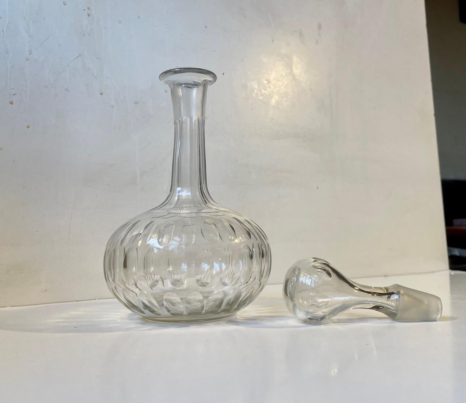 Beautiful cut crystal decanter from the 1920s. Made at Holmegaard in Denmark. The carafe is mouth-blown and cut with large ovale cuts around its perimeter. Its neck is multi-faceted and the drop-shaped stopper shares the same distinct Art Deco