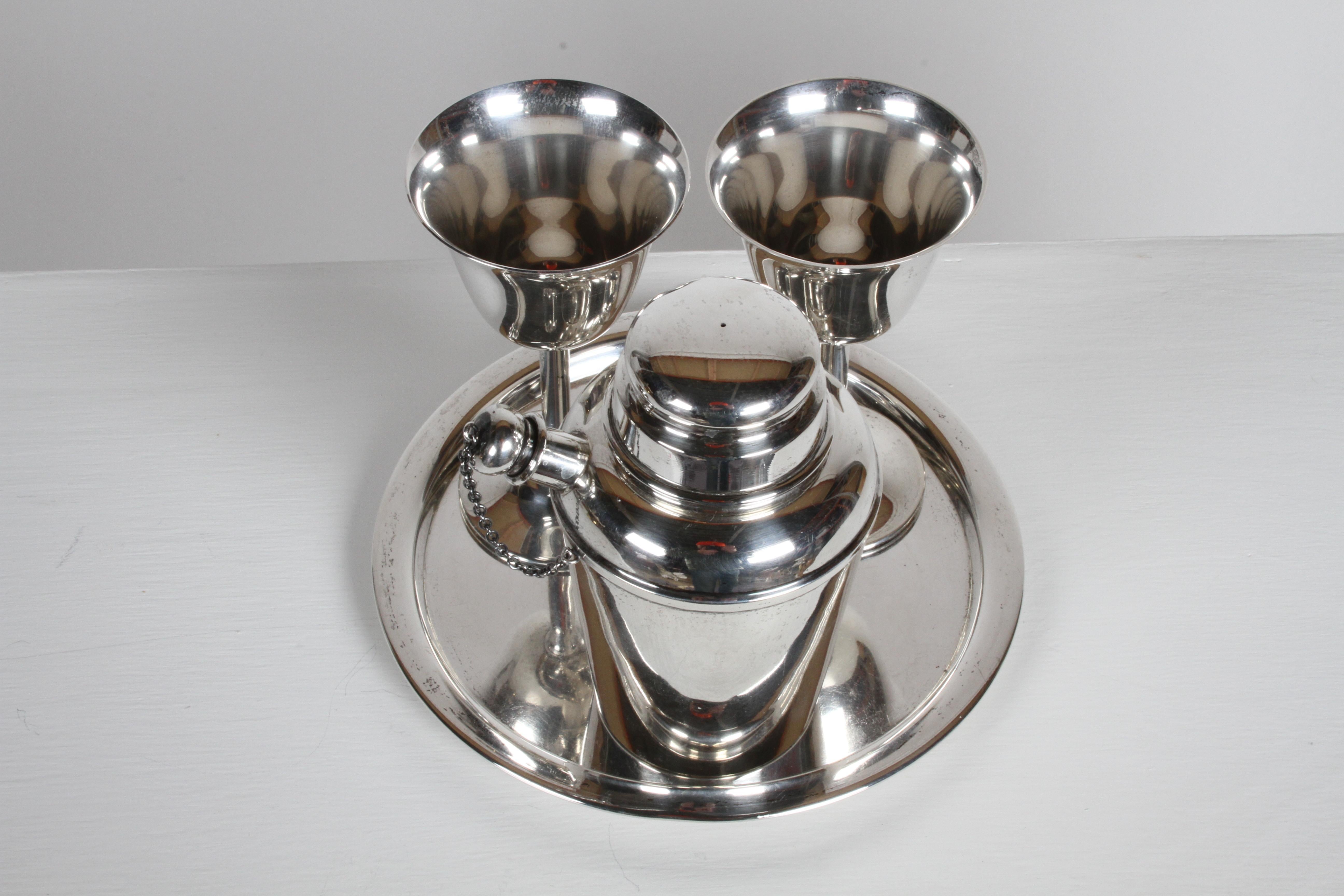 In the Art Deco style, this Reed & Barton sterling x110 cocktail shaker and tray were produced in the 1950s, the sterling goblets were made by Fisher. Shaker is a tapered cylinder design with removable lift-up dome lid, pronounced spout with stopper