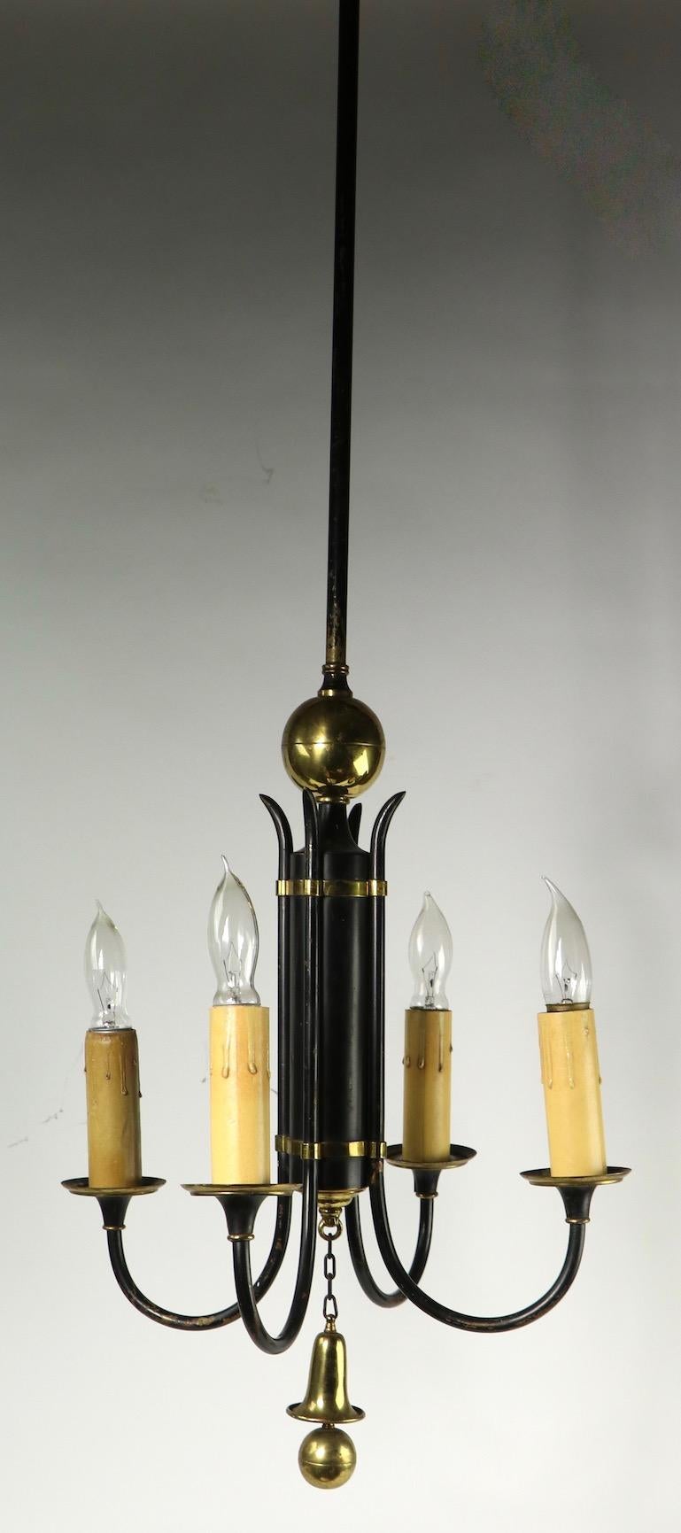 Stylish four-light chandelier, of black finished steel and brass trim. The fixture has four candle light sockets, attached to the cylindrical center body. This chandelier is good, original and working condition, it shows cosmetic wear to the finish,
