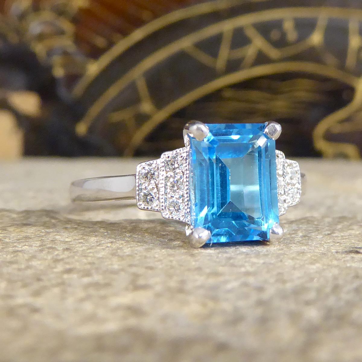 A beautiful ring has been hand crafted in an Art Deco style but is new and never worn. It has been designed and carefully crafted with a vibrant and bright Blue Topaz on the centre in a four claw setting with three milgrain set Diamonds tapering in