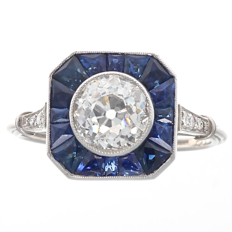 The perfect way to say I love you. Featuring a 1.37 carat old European cut diamond that is approximately I color, VS2 clarity. Gracefully surrounded by a halo of natural navy blue sapphires each calibrated to fit perfectly in the ring. Crafted in