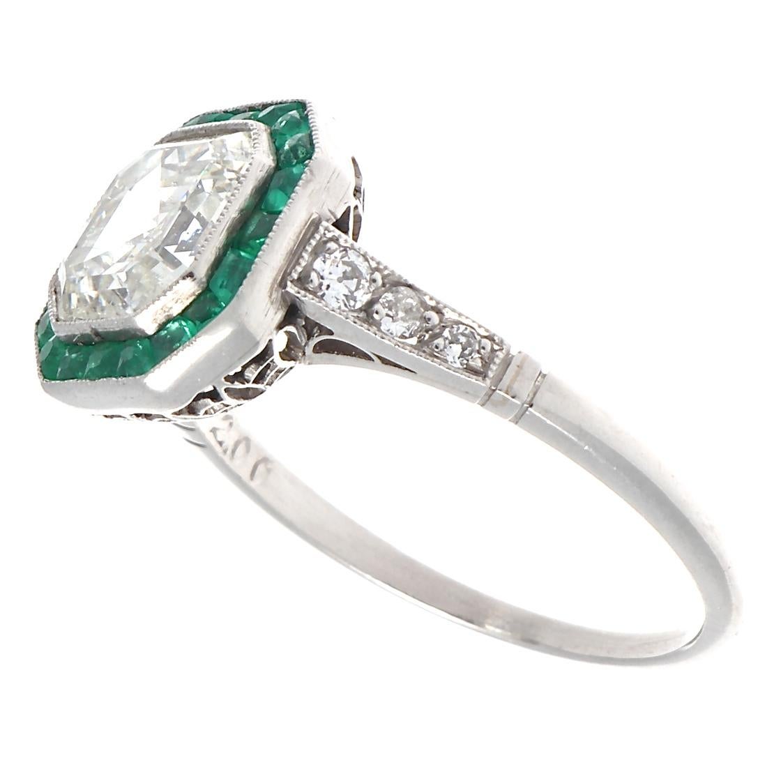 Stunning Art deco inspired ring featuring an elegant 2.00 carat Asscher cut diamond. Not only pleasing to the eye but easy on the pocketbook for such an outstanding ring. We grade as J-K color, VS2-SI1 clarity.  Accented with calibré cut emeralds,