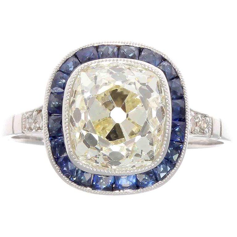 An engagement ring as timeless as a good lusty marriage. The ring is steeped in the tradition of the romantic and elegant art deco era. Designed with a 2.75 carat old mine cut diamond graded as M color, VS1 clarity. Accented by natural navy blue