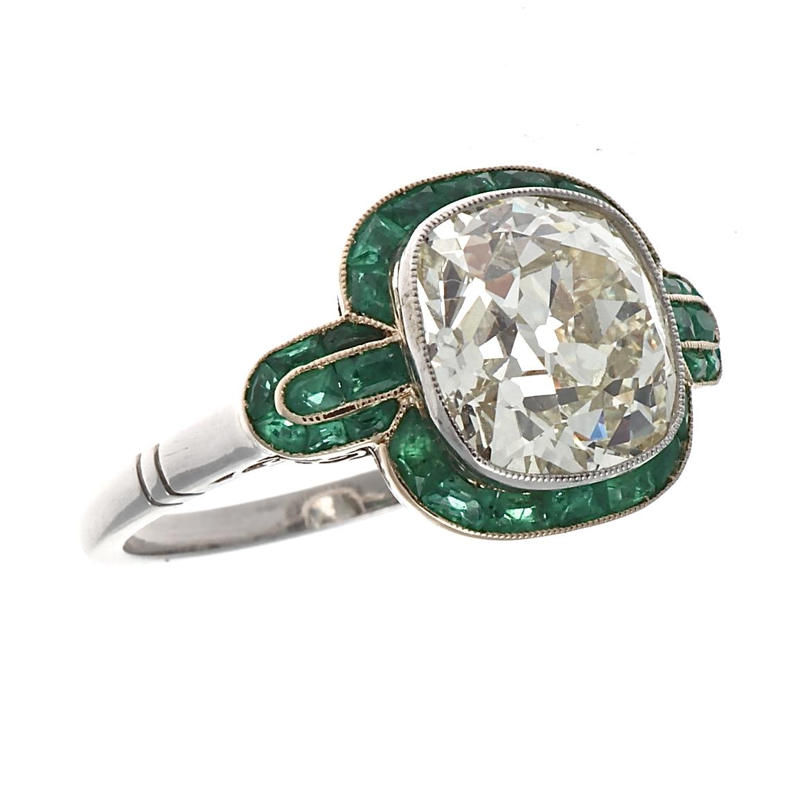 This Art Deco inspired ring features a  4.49 carat old European cut diamond that is approximately M color, VS clarity. Elegantly surrounded by perfectly calibrated vivid natural green emeralds accentuating the natural beauty of the center diamonds.
