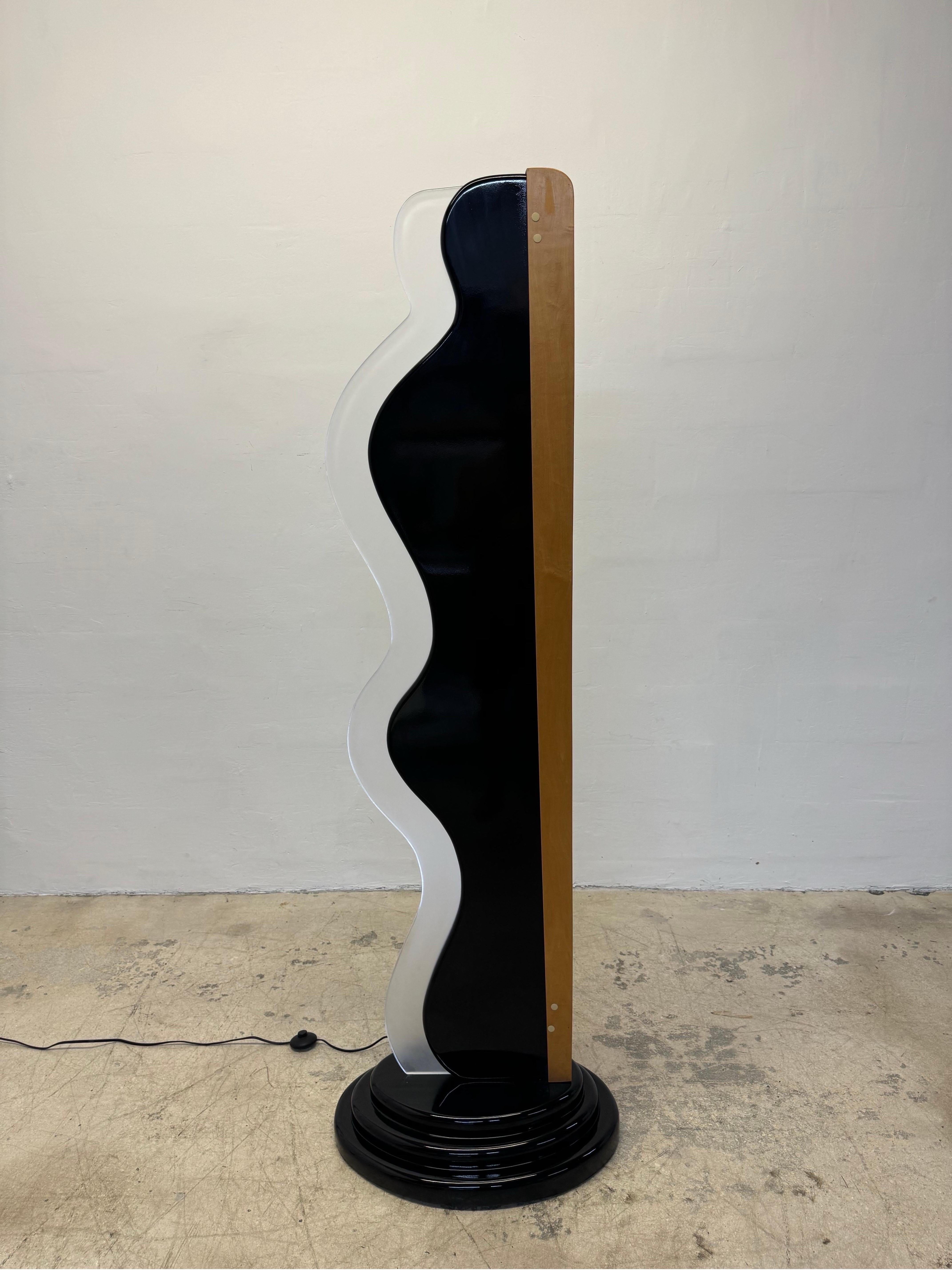 Custom art deco revival floor lamp with black lacquered base, wood veneer back and a curvy lucite front insert that reflects the light from an inner neon tube.  Circa 1980s.