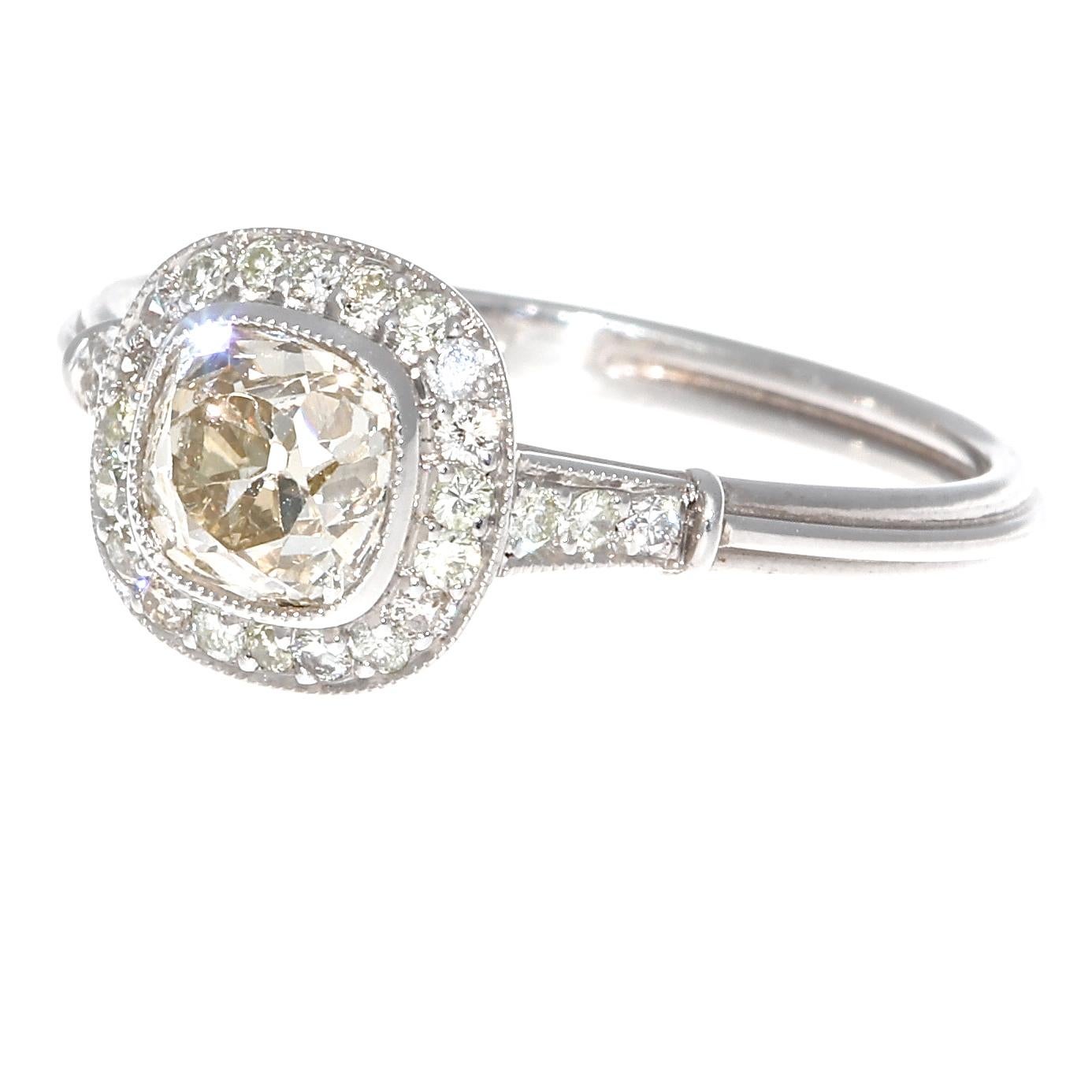 Tradition that lasts as long as a loving marriage. Featuring a 0.87 carat old mine cut diamond that displays a lovely natural light champagne color. Perfectly accented by a halo of near colorless diamonds. Hand crafted in platinum, ring size 7 and