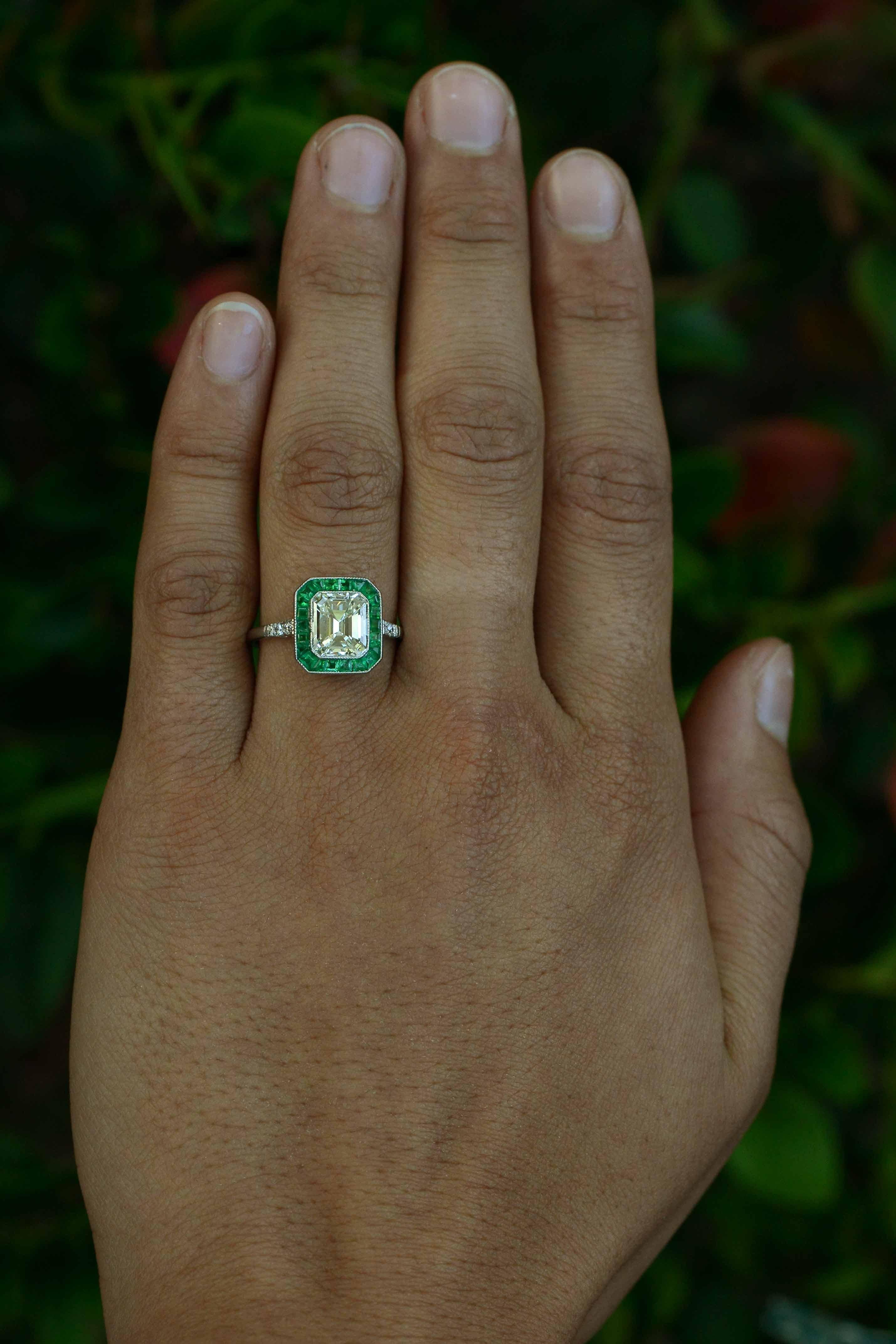 With a large and breathtaking, glittering, icy Emerald cut diamond taking center stage, the French-cut calibre' emerald halo surround really adds the wow factor. Owing to it's Art Deco heritage, this lovingly handmade platinum  engagement ring has