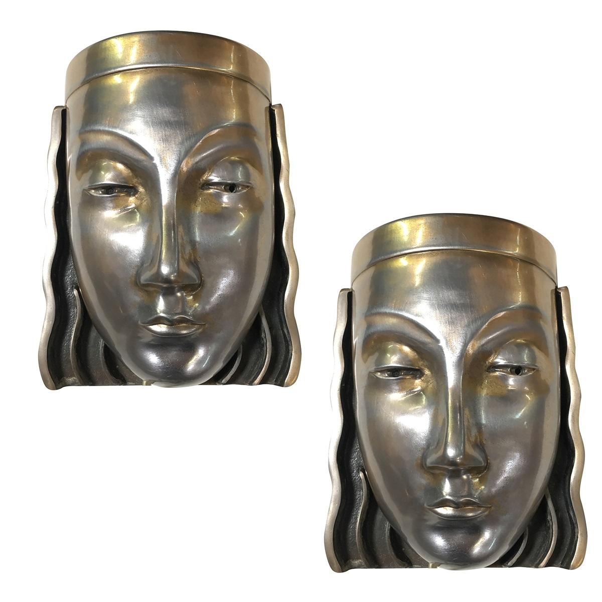 A pair of Art Deco styled female face mask wall sconces with a signature on the back marked 