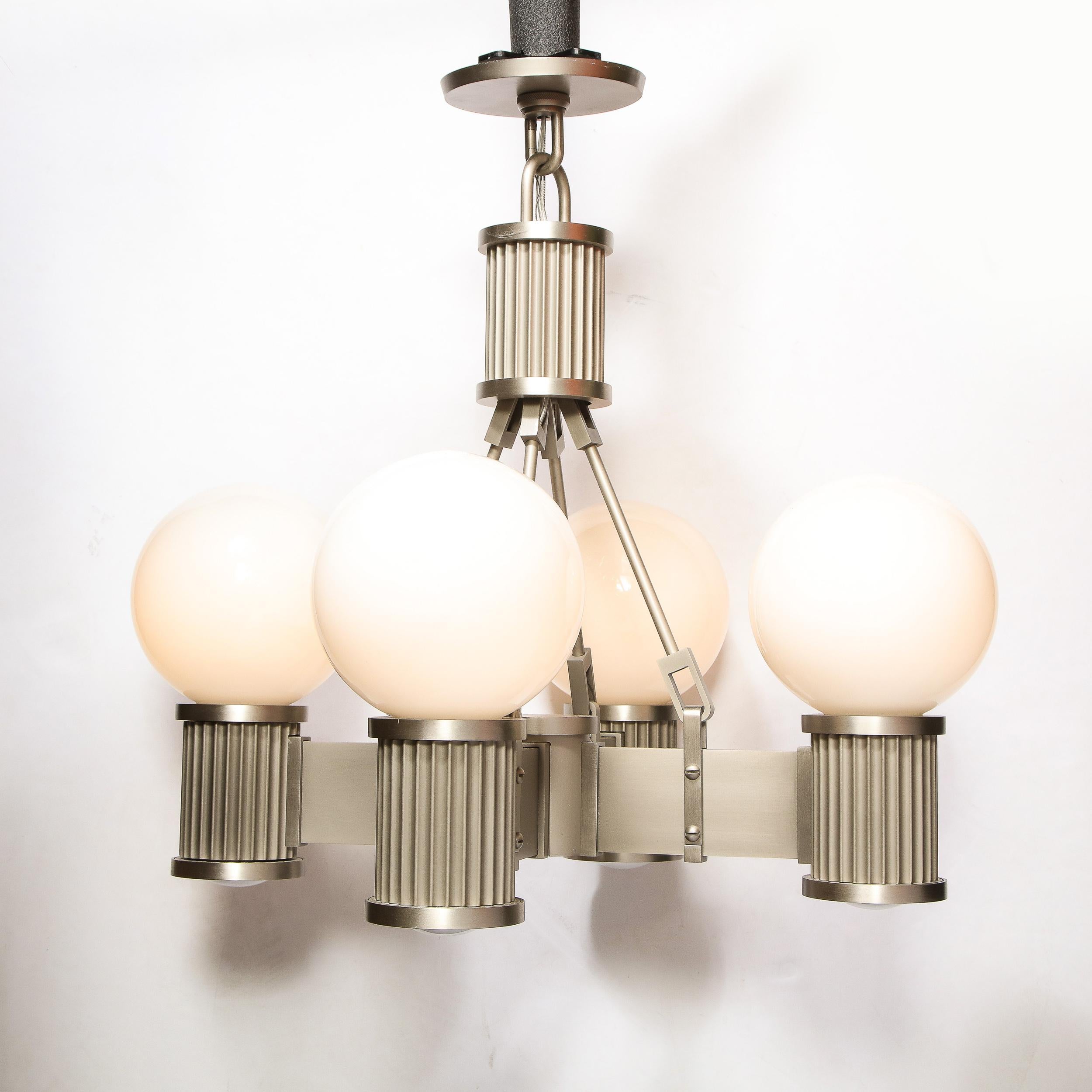 This stunning Art Deco chandelier was realized in the United States during the latter half of the 20th century. It features four rectangular arms that attach to a cylindrical central body. The arms culminate in cylindrical reeded supports that each