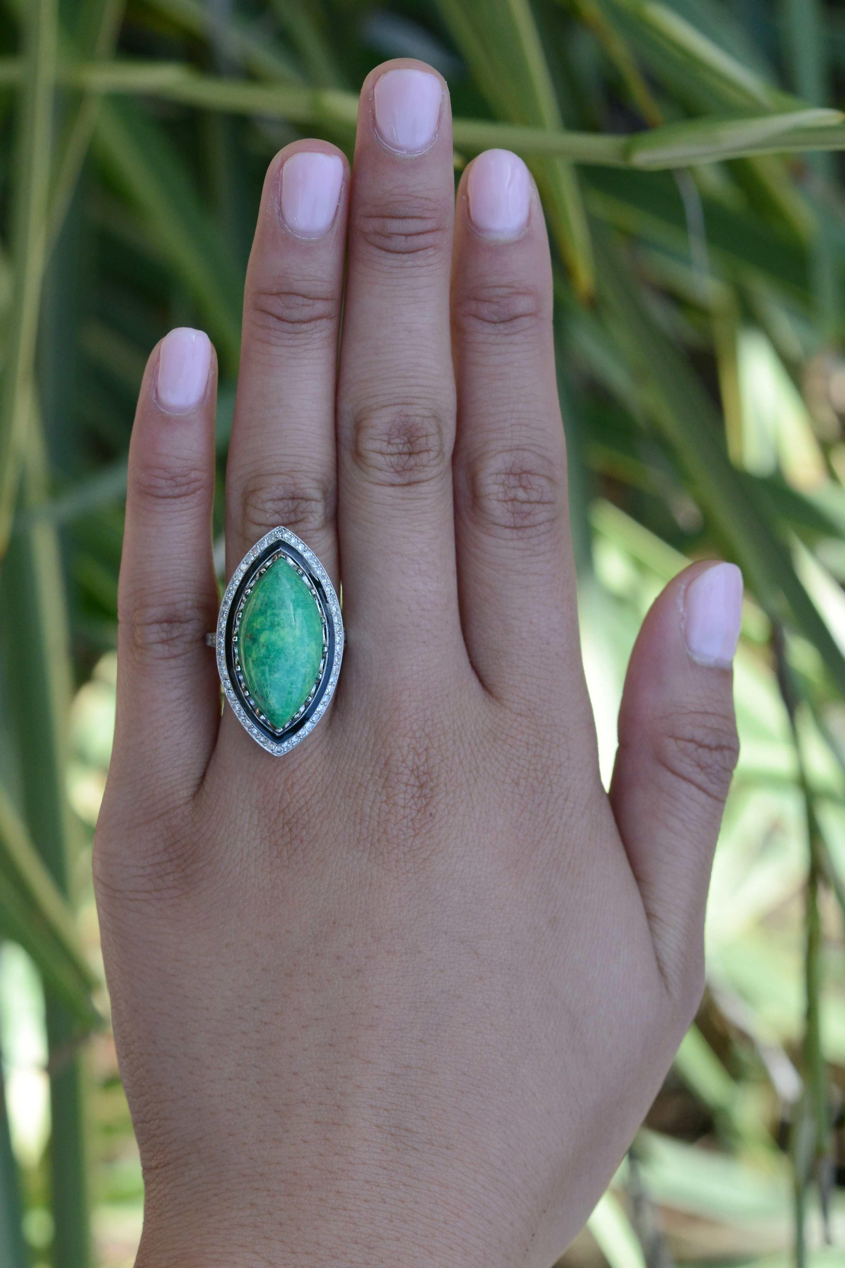 An elongated Art Deco inspired cocktail ring with a 27.86 carat, deeply saturated gem-quality green turquoise. The marquise-shaped cabochon cut is a most unique, elongated gemstone and is surrounded by a black enamel and diamond border. Entirely