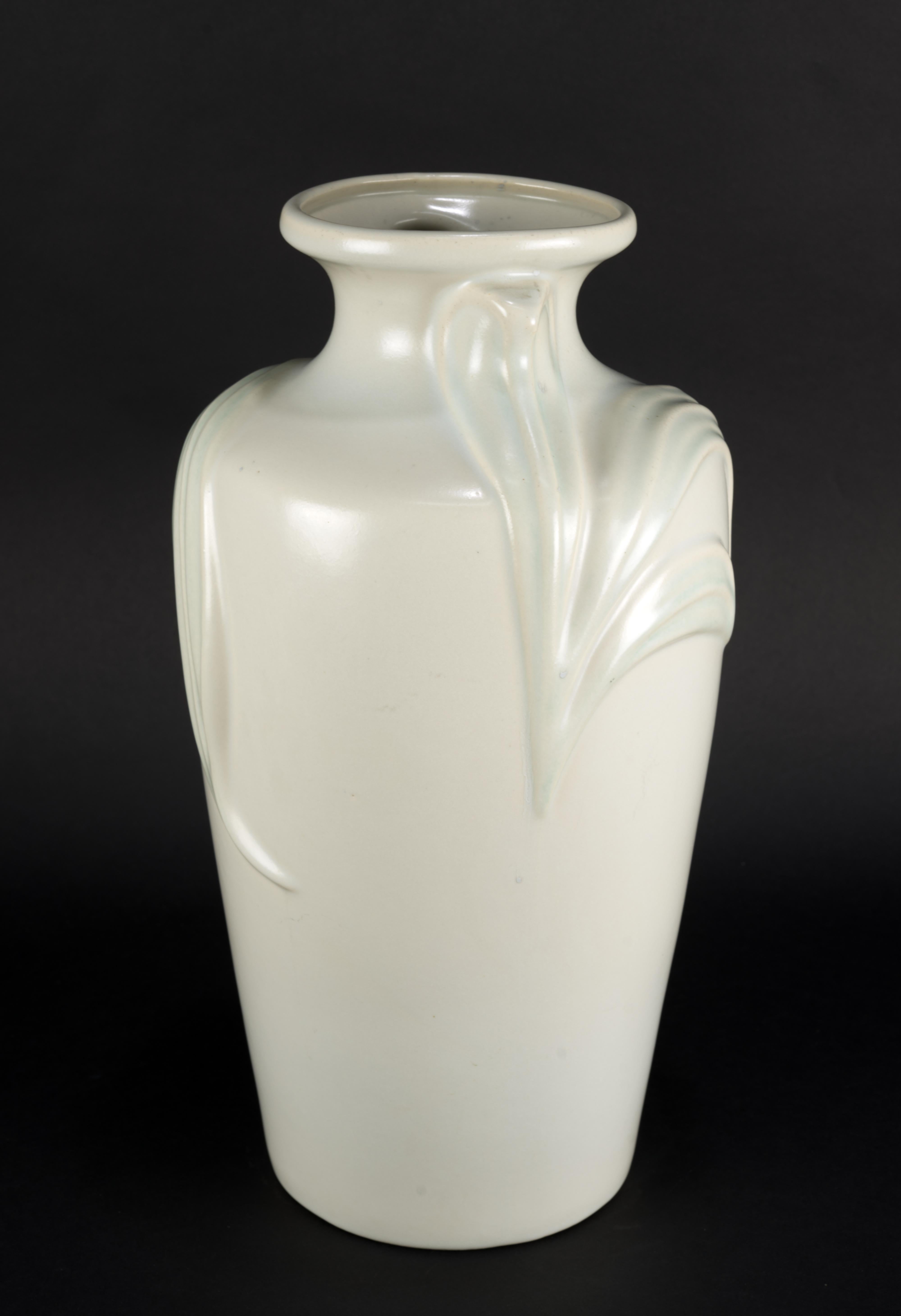  Large vase in semi-matte light blue and off-white glaze in Art Deco Revival style was made in 1980s by Harris Pottery out of Chicago, Illinois. The vase is decorated with relief of large leaves that are wrapping up around the top of the vase. The