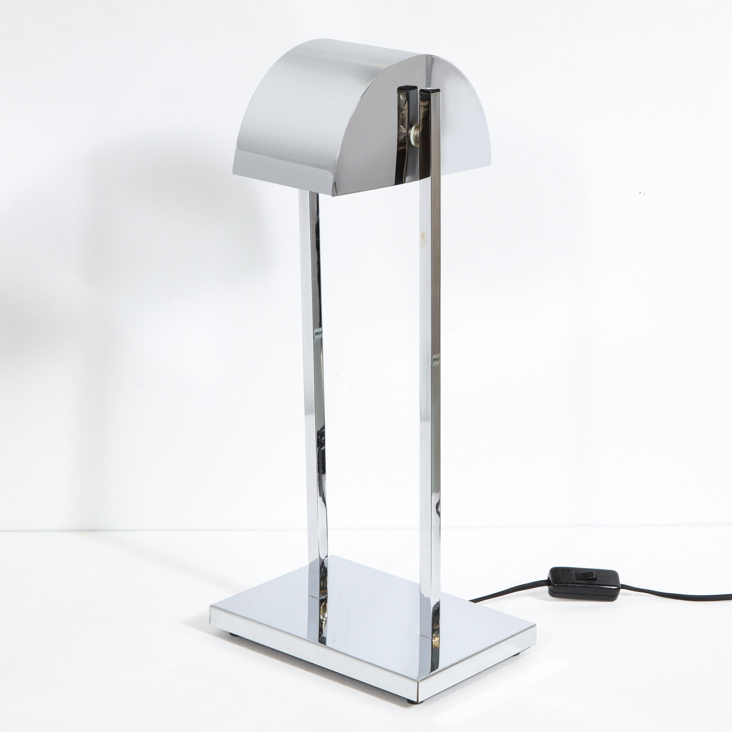 This stunning Art Deco revival table lamp features a rectangular base, volumetric rectangular supports and a convex streamlined shade, all in lustrous polished chrome. Inspired by the graphic forms and clean lines of the Machine Age, this piece is