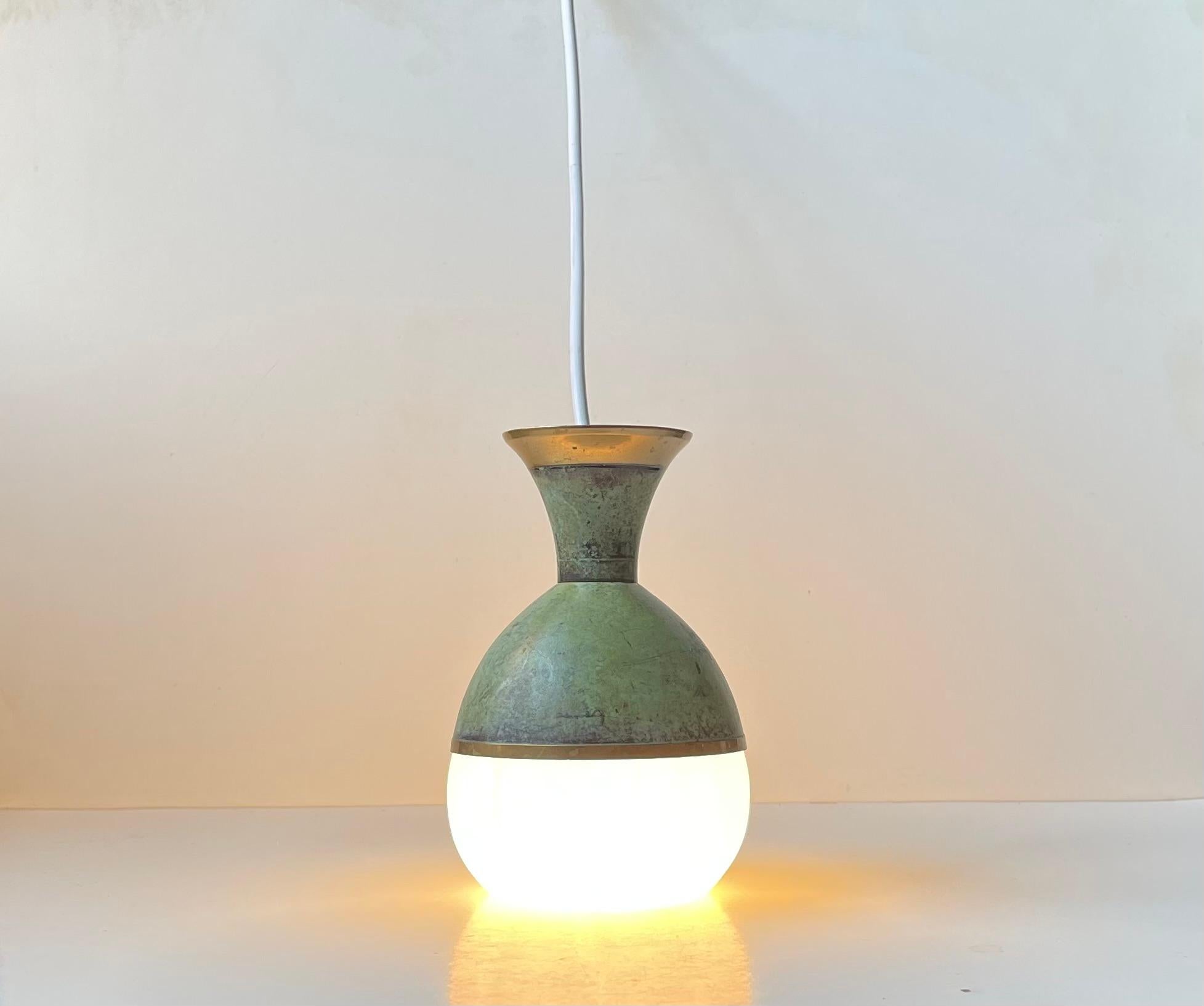 Unusual, possibly bespoke or up-cycled hanging pendant light in art deco style. It features a green verdigris patinated base/upper shade in which a white glass shade is supported. It was made in Scandinavia circa 1970s. 

The lamp is tested, new