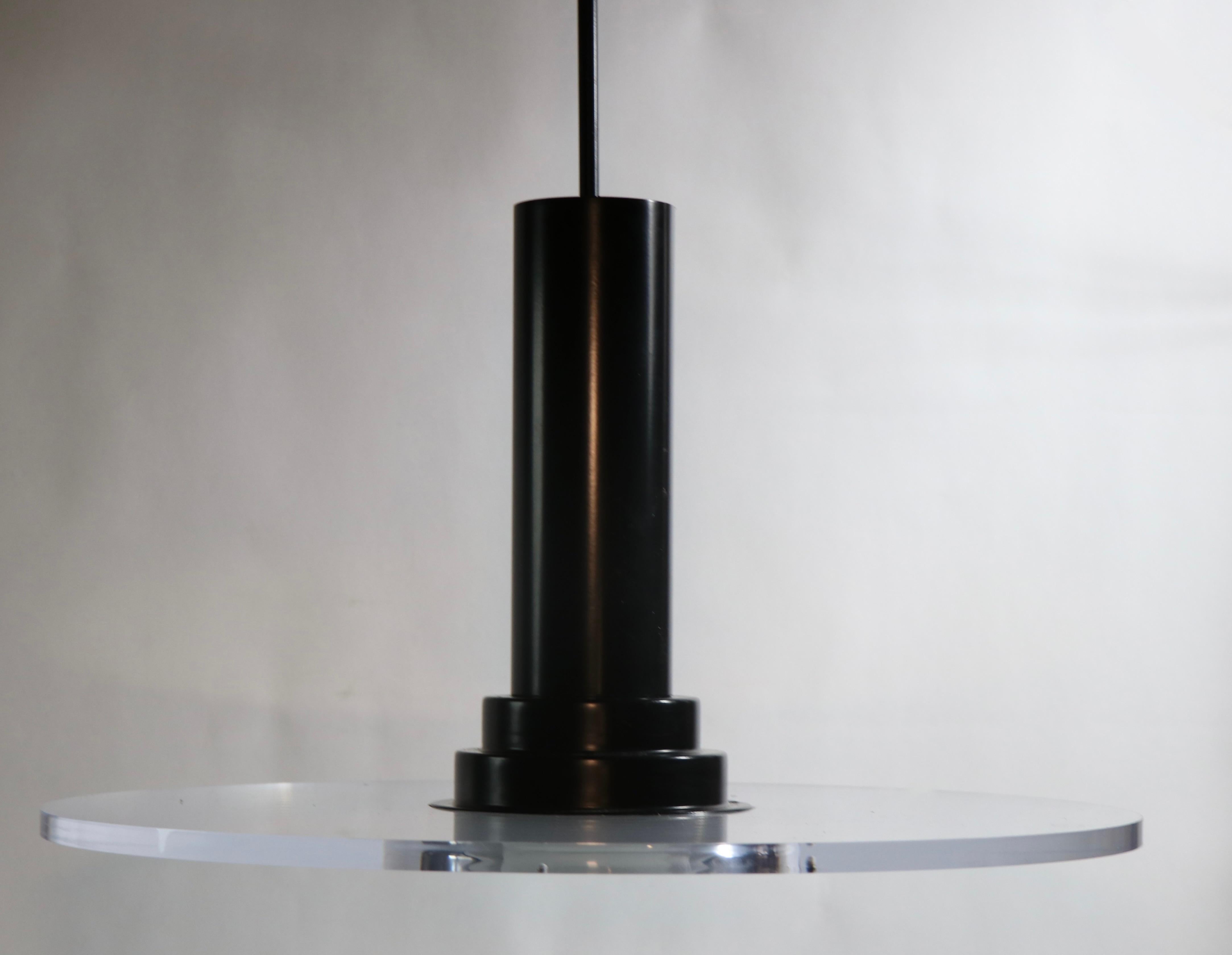 Stunning Post Modern, Art Deco Revival pendant light by noted maker Fredrick Ramond. The chandelier features a thick ( .50 in. ) transparent lucite disk, with graphic black metal hardware. Original, clean and working condition, fully and correctly
