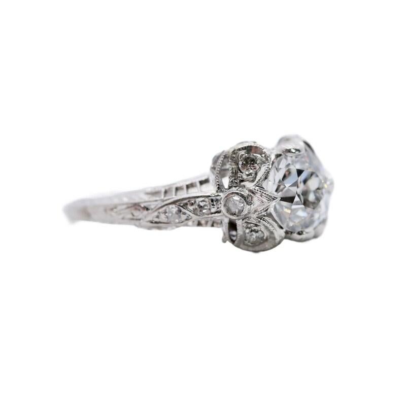 Aston Estate Jewelry Presents:

An Art Deco period diamond engagement ring in platinum. Centered by a 0.91 carat old European cut diamond of H color with VS2 clarity. Framed by diamond set ribbons and accented with hand engraved detailing. Pave set