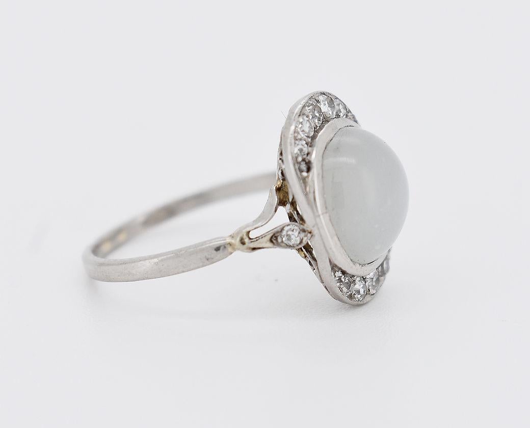 Art Deco period ring (circa 1920) in 18-carat gold (750 thousandths). It is adorned with a moonstone cabochon of approximately 3 carats (10 x 9.4 x 5 mm) surrounded by 14 diamonds totaling around 0.30 carats. The setting is embellished with a