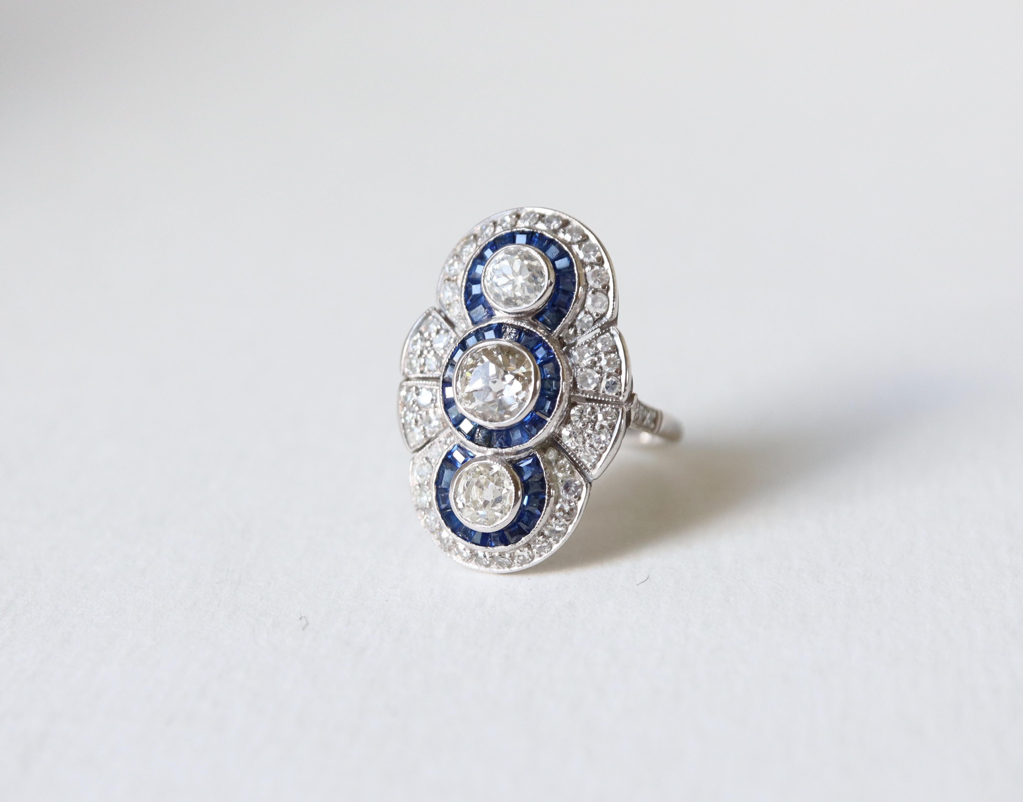 Marquise ring circa 1920-1930 in platinum set with calibrated diamonds and sapphires.
This ring with a typical geometric pattern from the 1920s-1930s is adorned with 3 larger diamonds weighing approximately 0.50 carat for the center one, and 0.25