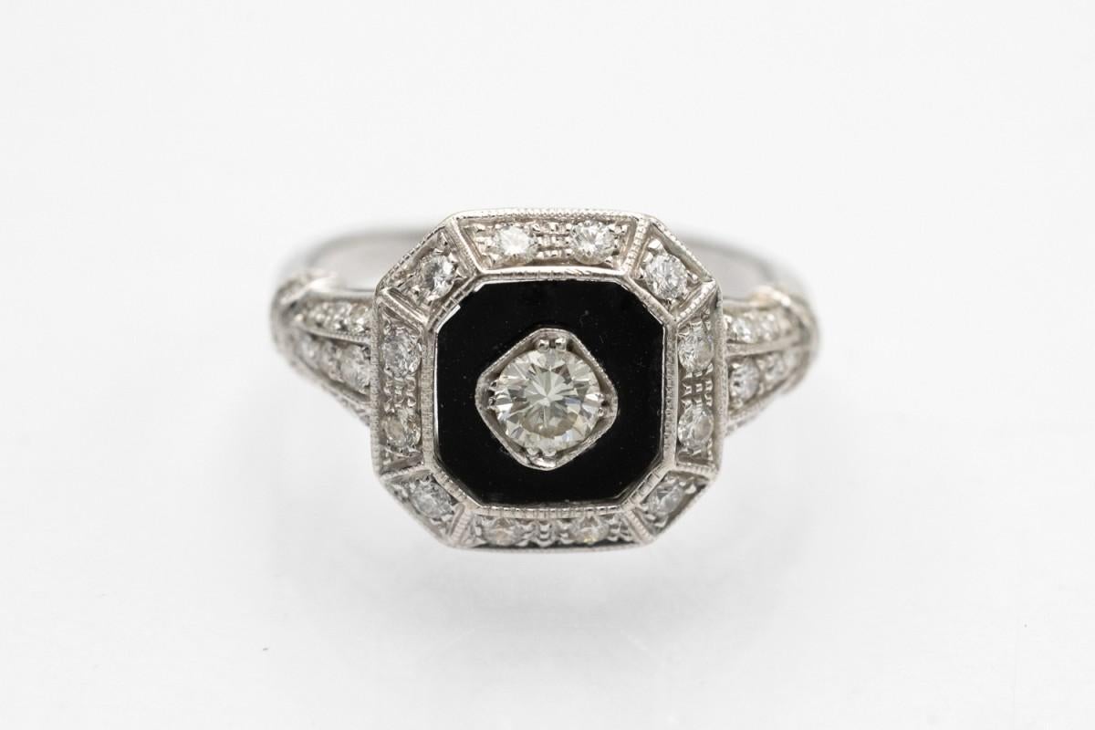 Art Deco ring made of 18-karat white gold (0.750 fineness) with an octagonal onyx and 37 diamonds.

The central point of the ring is a brilliant-cut diamond weighing 0.21 ct (VS clarity, K color).

Additionally, the ring is decorated with 36