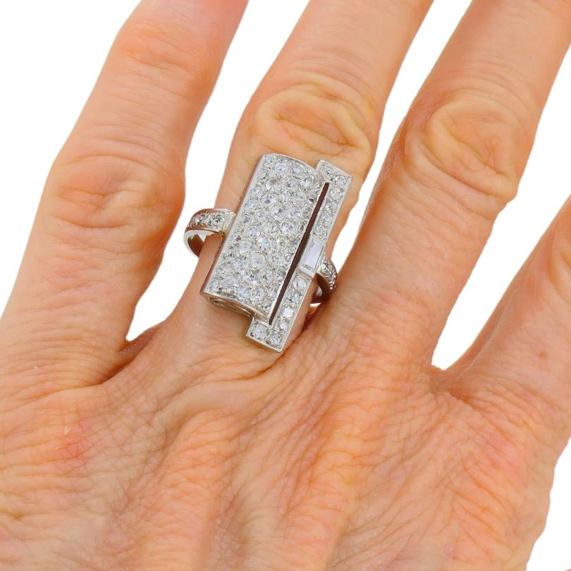 Uno spettacolare anello di diamanti Art Deco francese in platino e oro bianco 18 carati.  
Il centro dell'anello presenta un pannello di platino leggermente curvo, ornato da un'abbagliante serie di diamanti di taglio Vecchio Europeo. Il pannello è