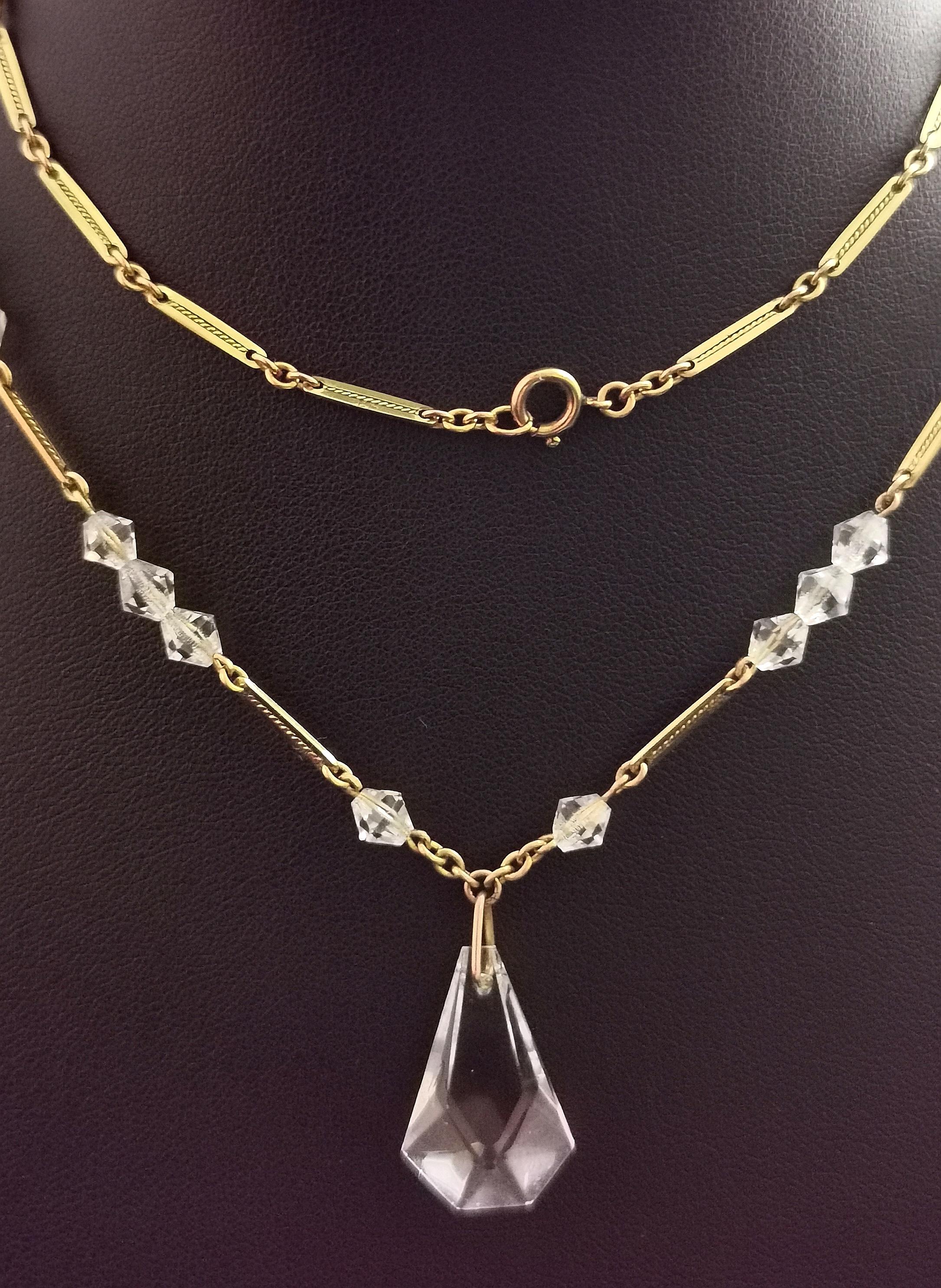 A beautiful vintage Art Deco 9ct yellow gold and rock crystal pendant necklace.

The necklace is made up from fancy bar links with engraved detailing to each in a rich 9ct yellow gold.

There is a single geometric cut rock crystal pendant suspended