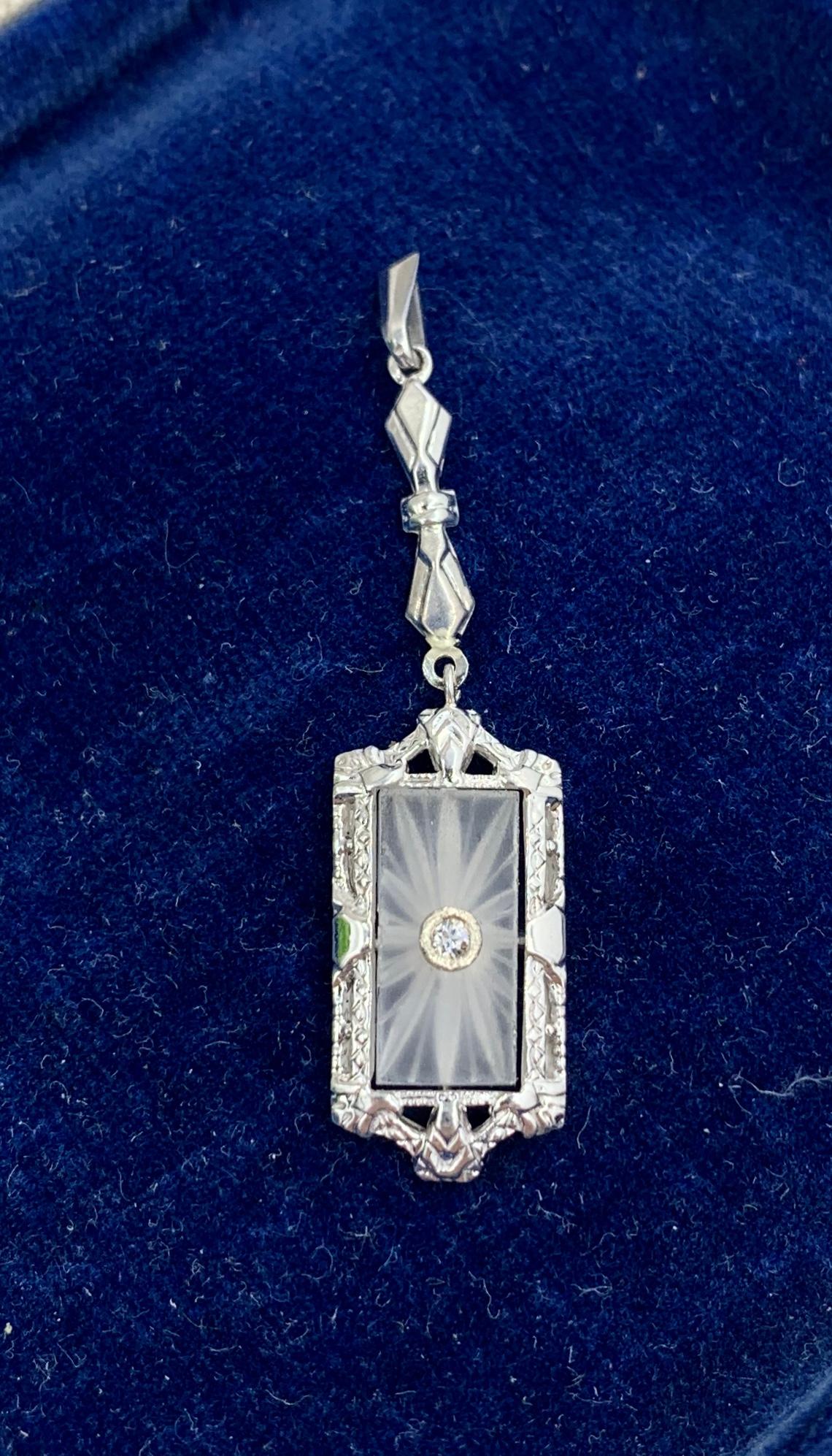 This is a very special antique Edwardian, Art Deco pendant with a central panel of carved Rock Crystal with an Old Mine Cut Diamond in the center and and exquisite engraved garland motif design in 14 Karat White Gold. 
This is one of the most