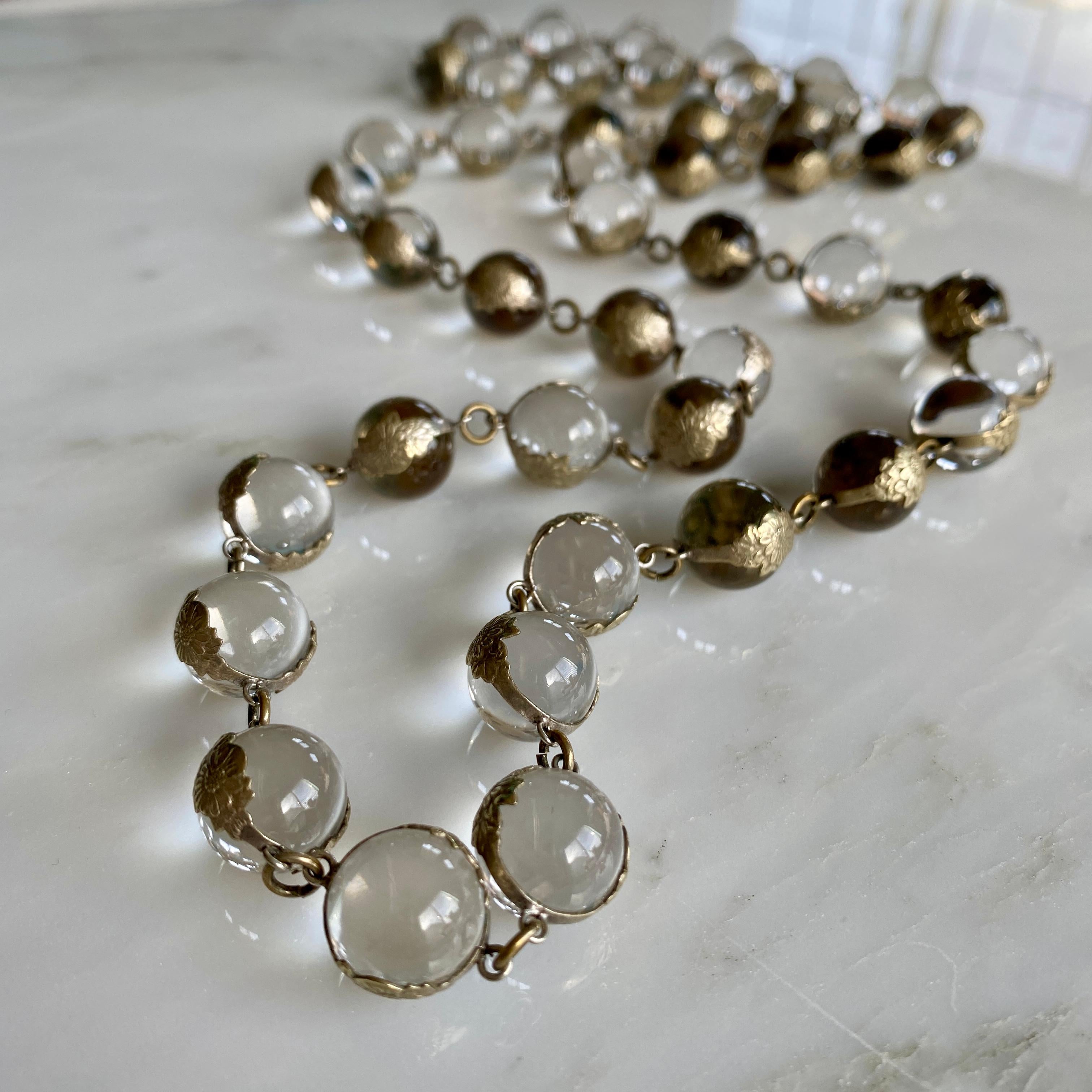 Details:
Fabulous Art Deco Pools of Light necklace in sterling silver. Necklace is in wonderful condition, and is 36 inches in length. The 45 clear orbs making up the balls Pools of Light are un-drilled, and held in place with floral silver gilt