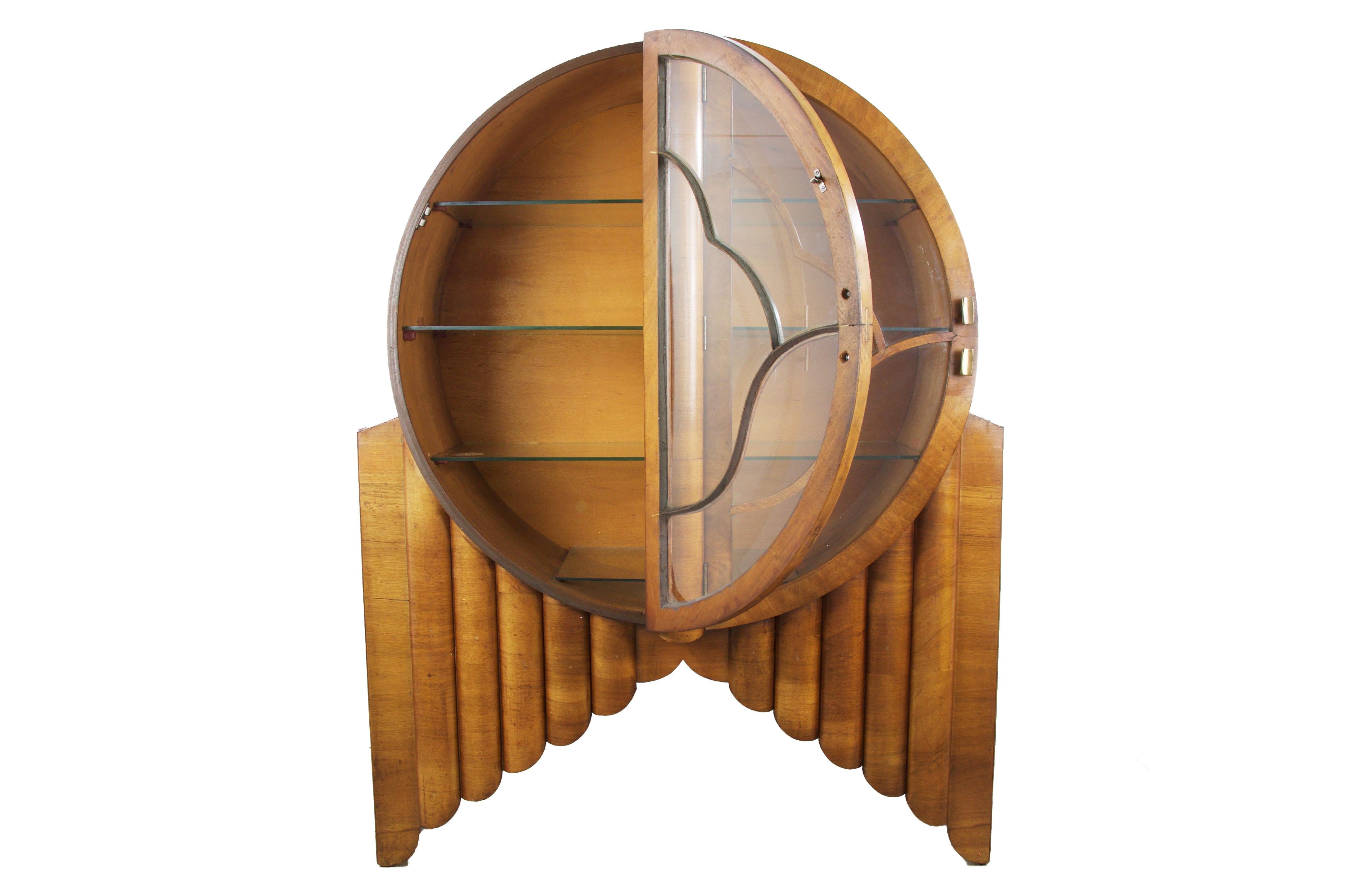 This is the sought-after Art Deco 'Rocket' Cabinet Display Vitrine, English, circa 1930.
Figured walnut with six graduated tubular-shaped columns on each side representing a rocket launch and the doors glazed separately in the form of stylized