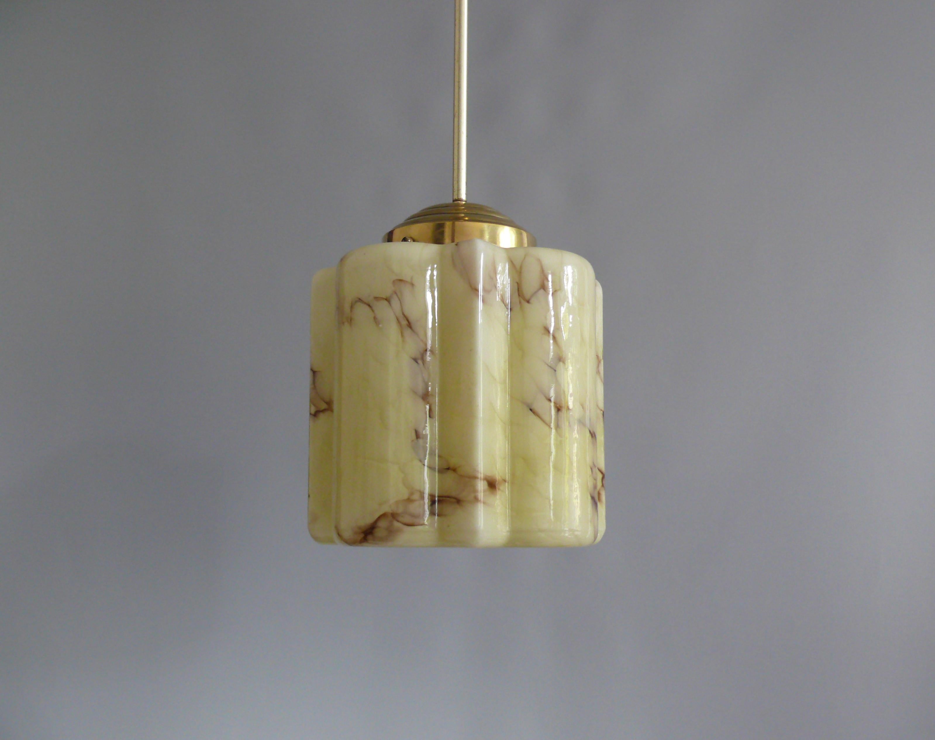 Art Deco rod pendant light from the 1930s - 1940s with a very nicely profiled beige glass shade. The glass shade is marbled and is in very good condition. The suspension is made of brass and has been stylishly renewed from stock. The entire