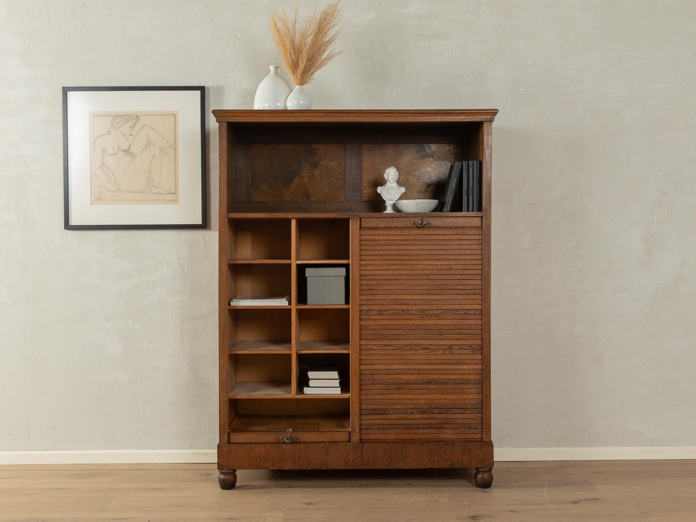 Unique Art déco roller shutter cabinet from the 1920s. Corpus in dark stained oak veneer with sixteen shelves and time-typical feet.

Quality Features:
very good workmanship
high quality materials
Made in Germany

Measurements (Compartments): W 26