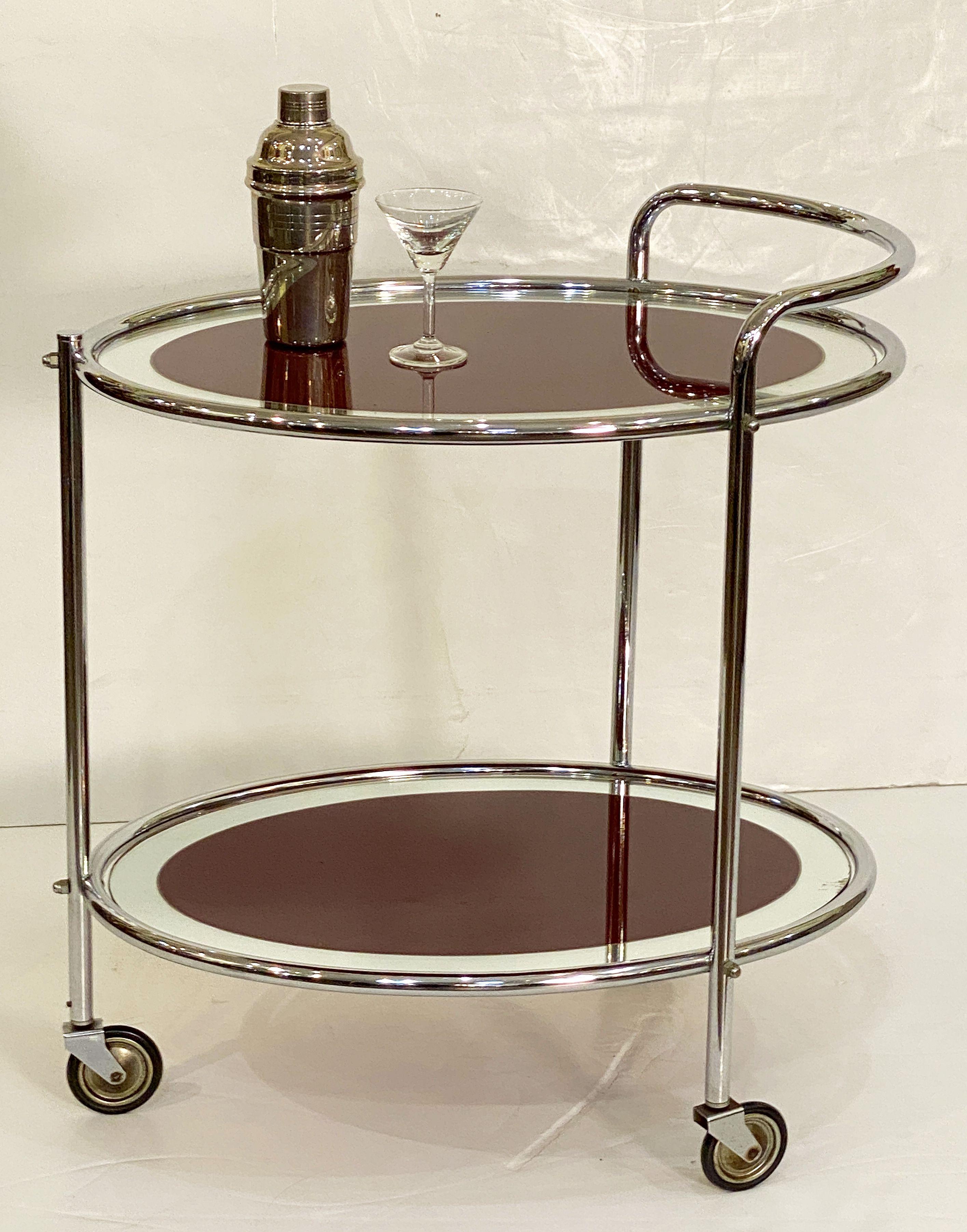A fine English drinks trolley or bar cart of chrome and mirrored glass from the Art Deco era, featuring two oval mirrored glass tiers on stylish chrome mounts and standing on three vintage rolling casters.