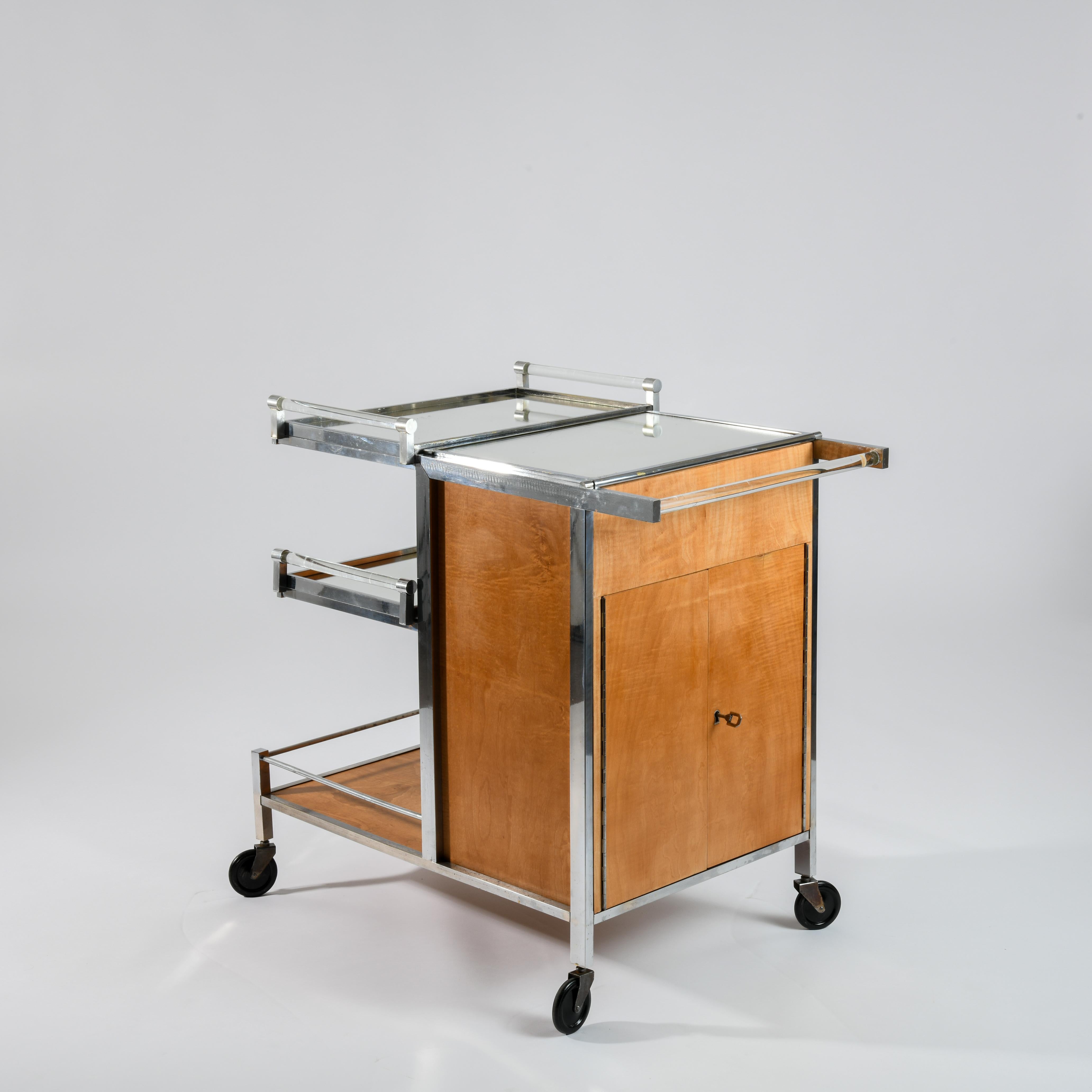 Rolling bar by Jacques Adnet circa 1932 with quadrangular body in sycamore wood, chromed metal, lacquered metal and glass. Published by La Compagnie des Arts français. It opens with two doors with key, including in the interior part chromed supports