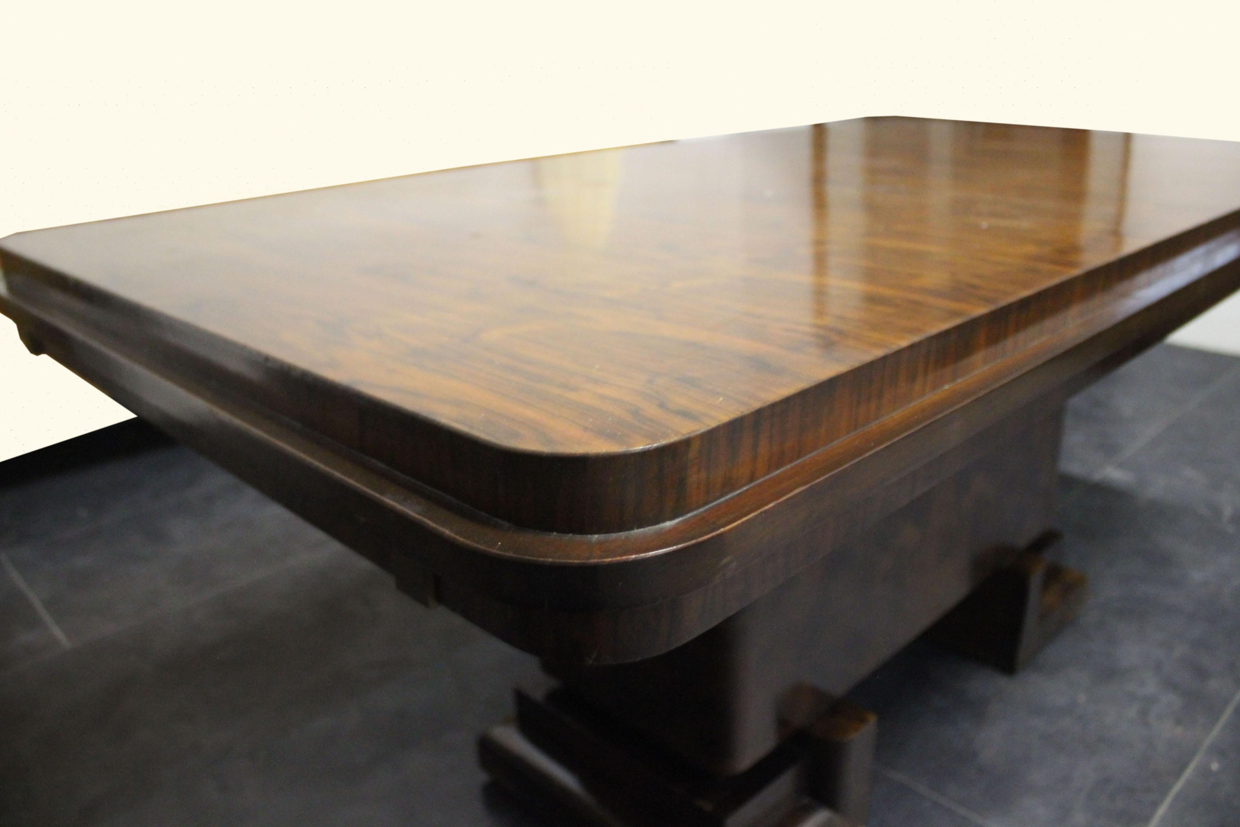 Table art déco, la base avec 2 étagères continues formant un u sont de style cubiste et soutiennent le corps central en palissandre briar. Le plateau d'une épaisseur généreuse est en plume de palissandre qui suit parfaitement le bord jusqu'au