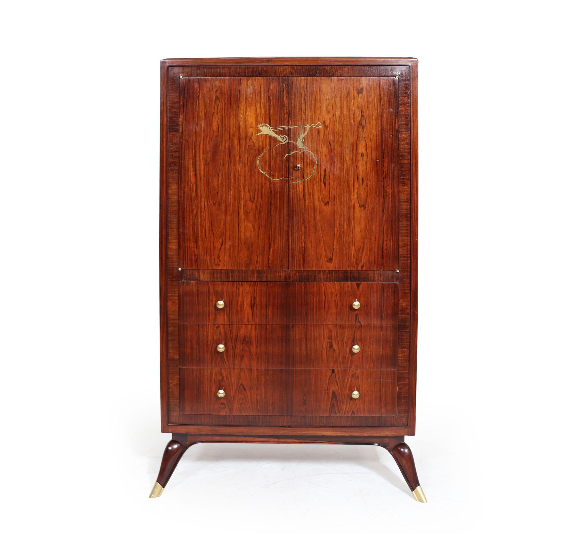 An Art Deco Rosewood cabinet having three long drawers with cupboards above, behind the doors is lightwood lined with a shaped shelf, to the front of the doors is a lady on a chariot inlayed in bronze to the manner of Jacques Ruhlmann the solid