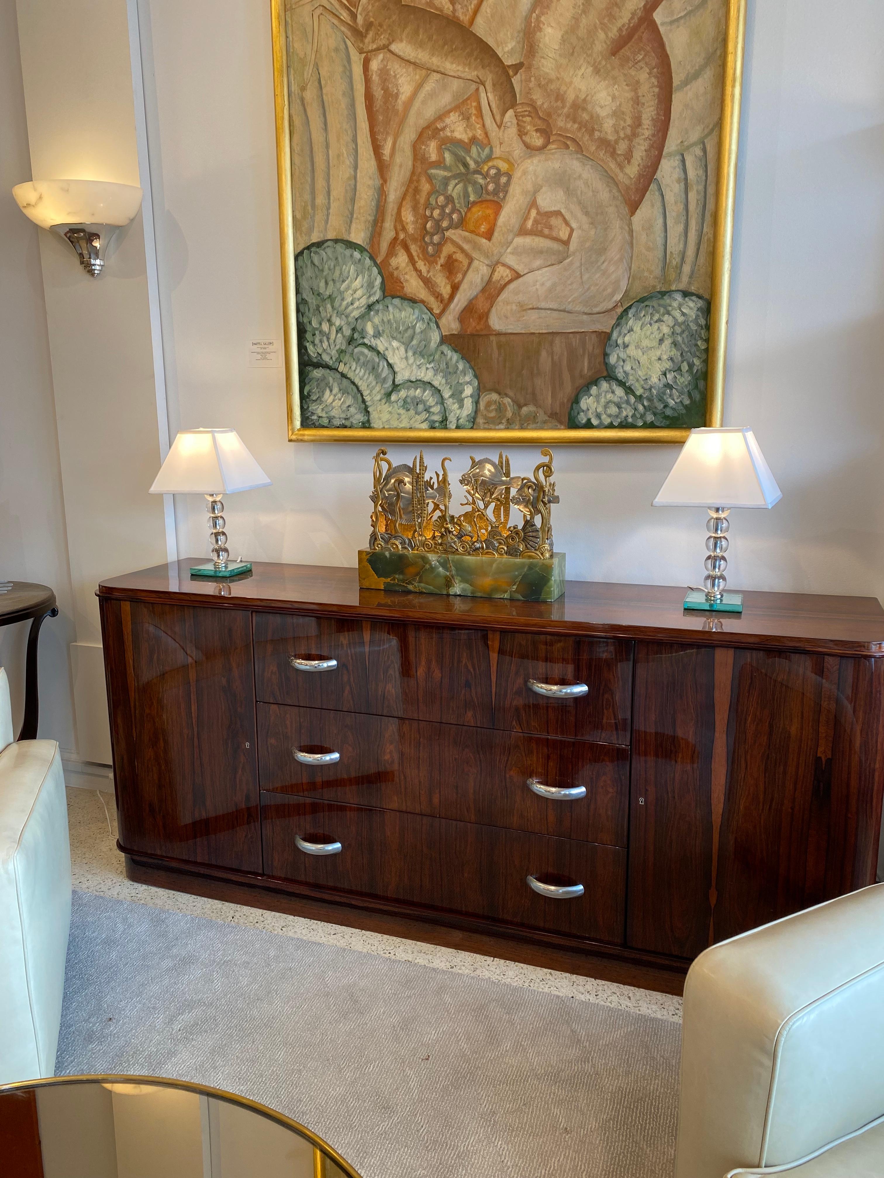 An Elegant Art Deco Rosewood buffet/sideboard with three drawers in the center with nickel handles and 2 doors on each side with shelves inside designed by Jacques Adnet.

Jacques Adnet was an iconic Art Deco French designer. His designs featured