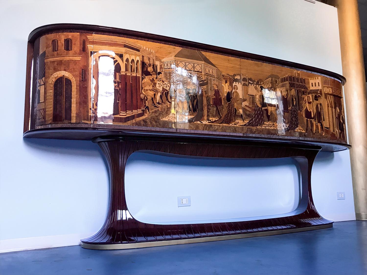 Italian masterpiece extremely rare, created by Vittorio Dassi around the 1940s-1950s, frontally all decorated with a spectacular marquetry ascribed to the execution of Piero del Grande.
The sideboard is sitting on a sculptured rosewood structure,