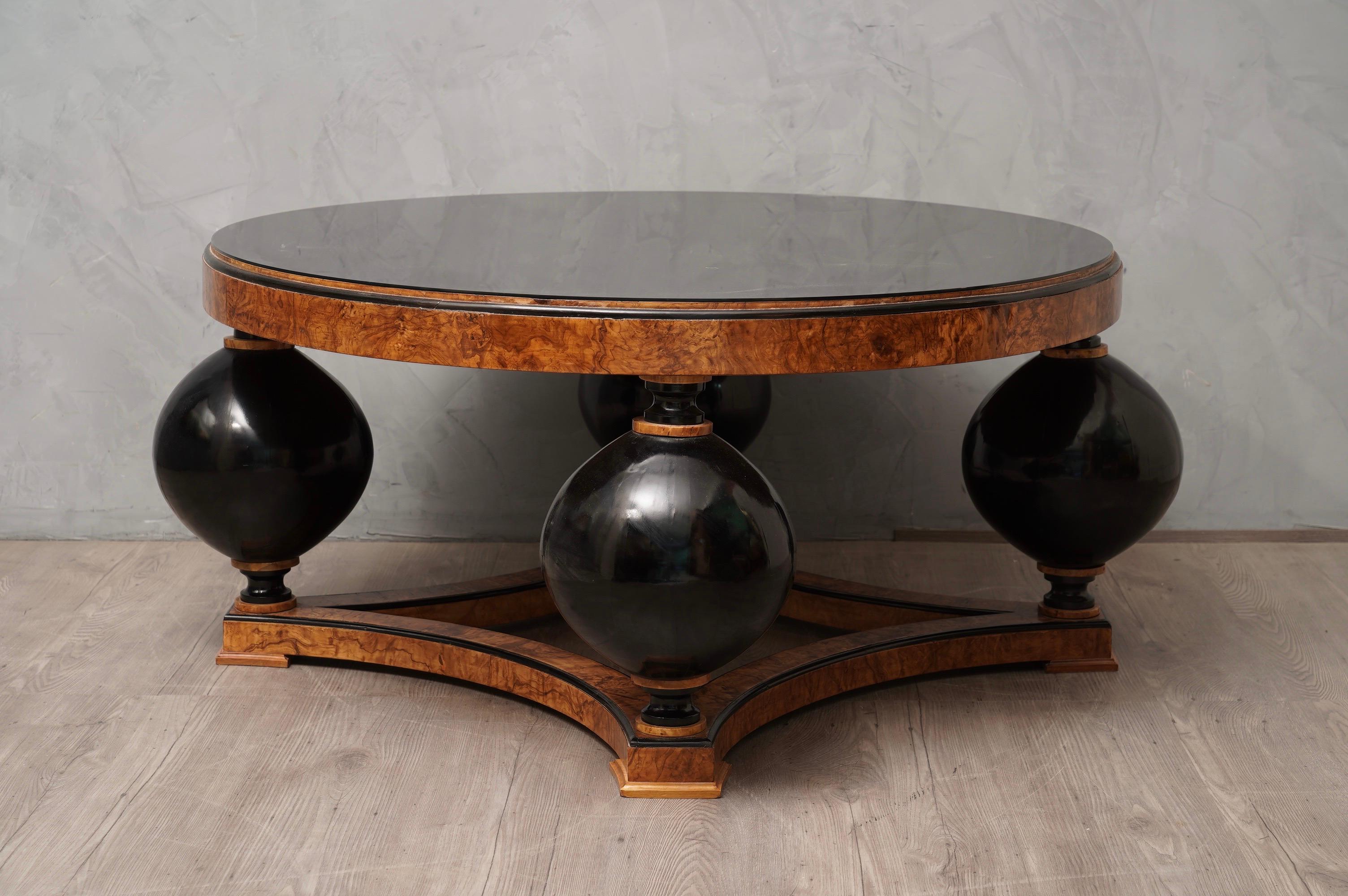 Sofa Table with a beautiful veneer in olive ash wood, to notice the beautiful design of the legs.

All veneered in ash wood. The round top has a black glass placed on top. Below are four large wooden balls polished in black shellac. While the foot